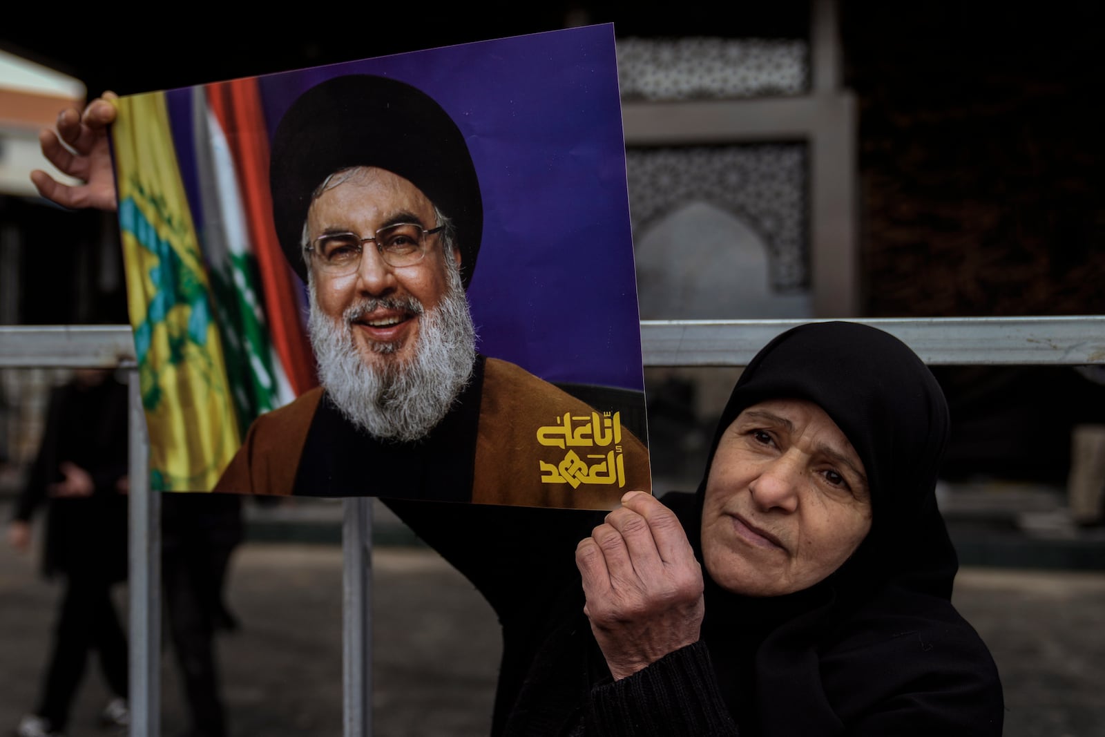 An Hezbollah supporter holds a picture of the late Lebanon's Hezbollah leader Sayyed Hassan Nasrallah, who was killed on Sept. 27, 2024 by Israeli airstrikes, as she stands at the burial site during preparations a day ahead of his public funeral procession in Beirut, Lebanon, Saturday, Feb. 22, 2025. (AP Photo/Bilal Hussein)