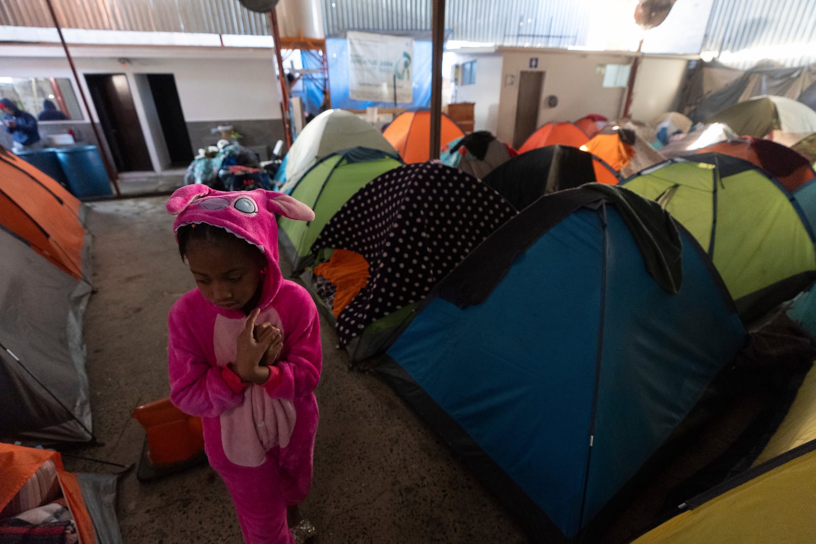 Maickeliys Rodriguez, 6, of Venezuela, leaves her tent at a migrant shelter on a chilly morning in Tijuana, Mexico, Saturday, Feb. 1, 2025. (AP Photo/Gregory Bull)