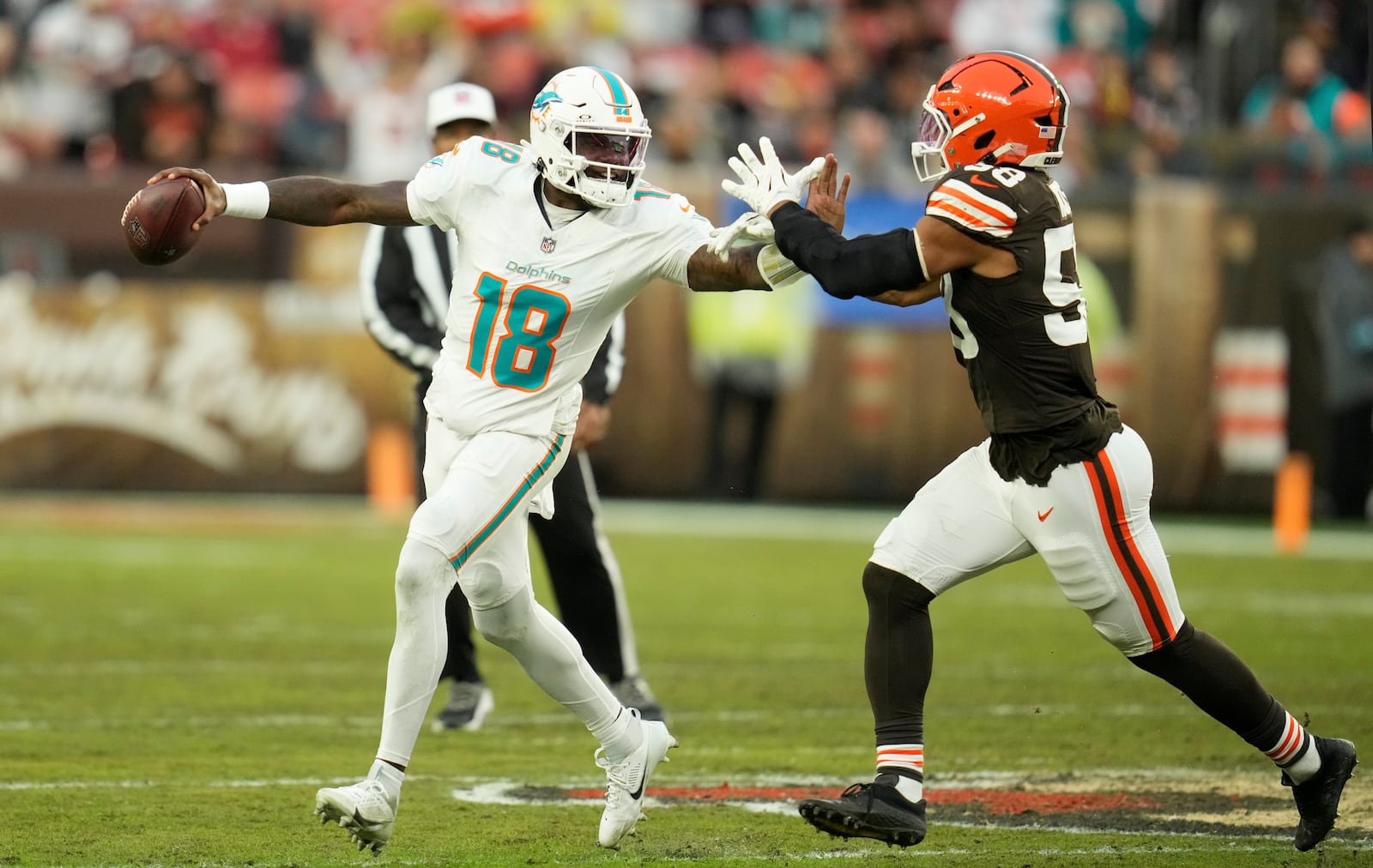 Miami Dolphins quarterback Tyler Huntley (18) is pressured by Cleveland Browns linebacker Jordan Hicks (58) during the first half of an NFL football game Sunday, Dec. 29, 2024, in Cleveland. (AP Photo/Sue Ogrocki)