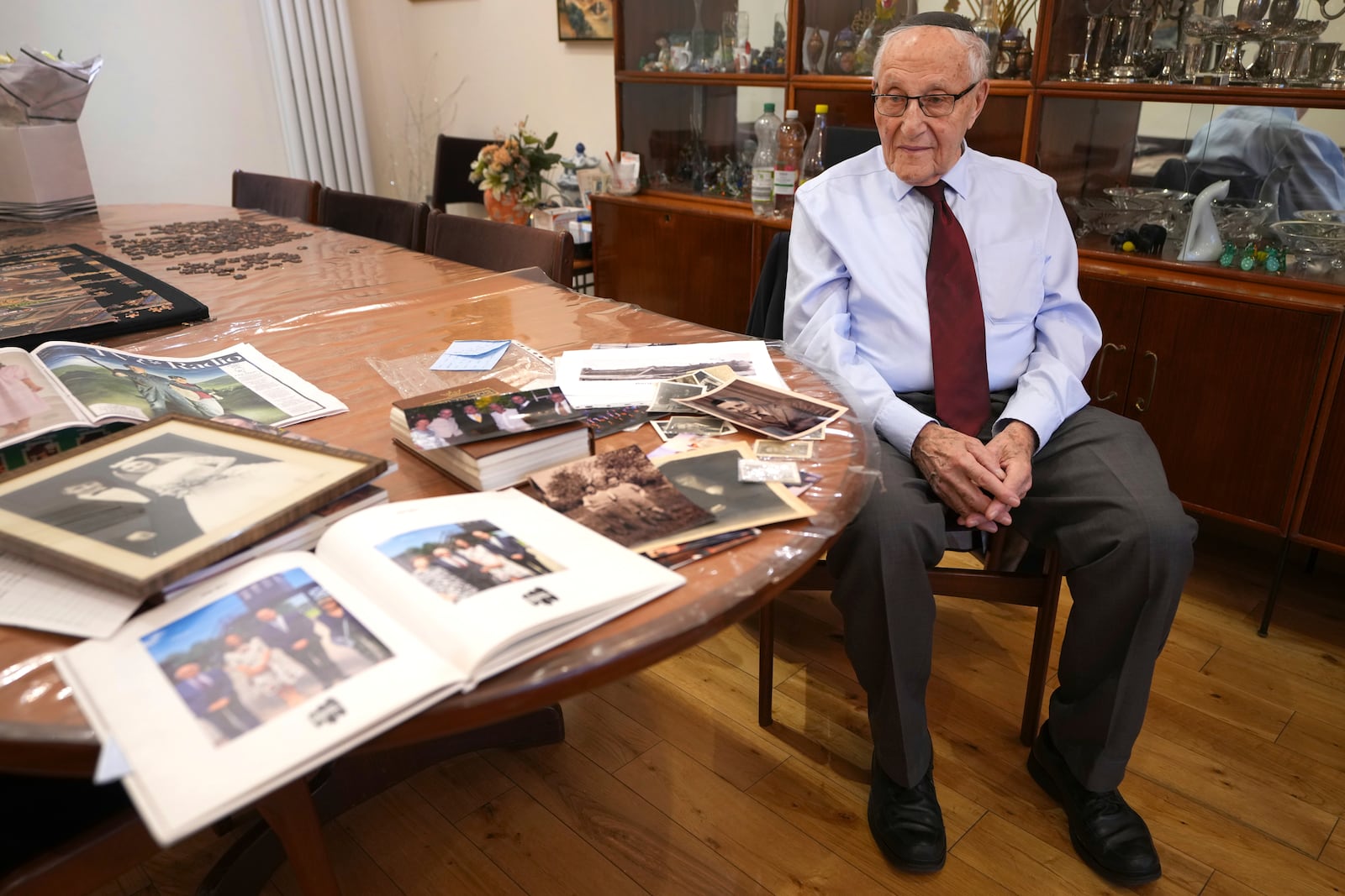 Manfred Goldberg, a Holocaust survivor looks across photographs as he is interviewed in London, Wednesday, Jan. 22, 2025. (AP Photo/Kirsty Wigglesworth)