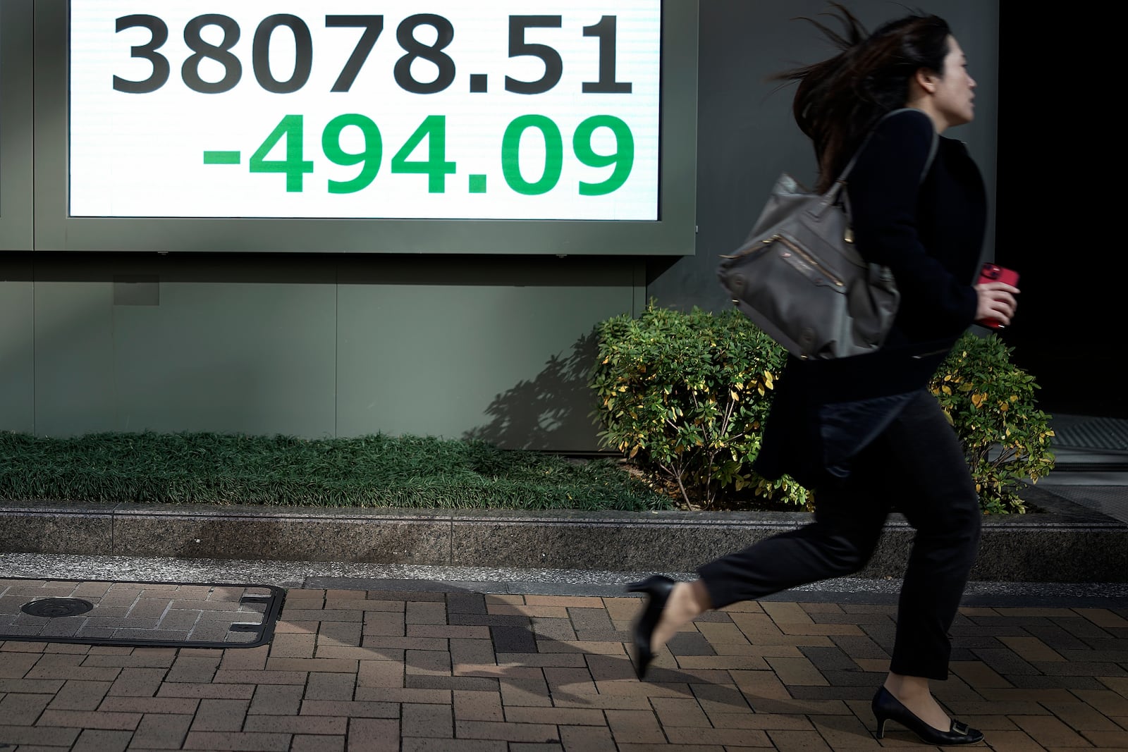 A person runs in front of an electronic stock board showing Japan's Nikkei index at a securities firm Friday, Jan. 17, 2025, in Tokyo. (AP Photo/Eugene Hoshiko)