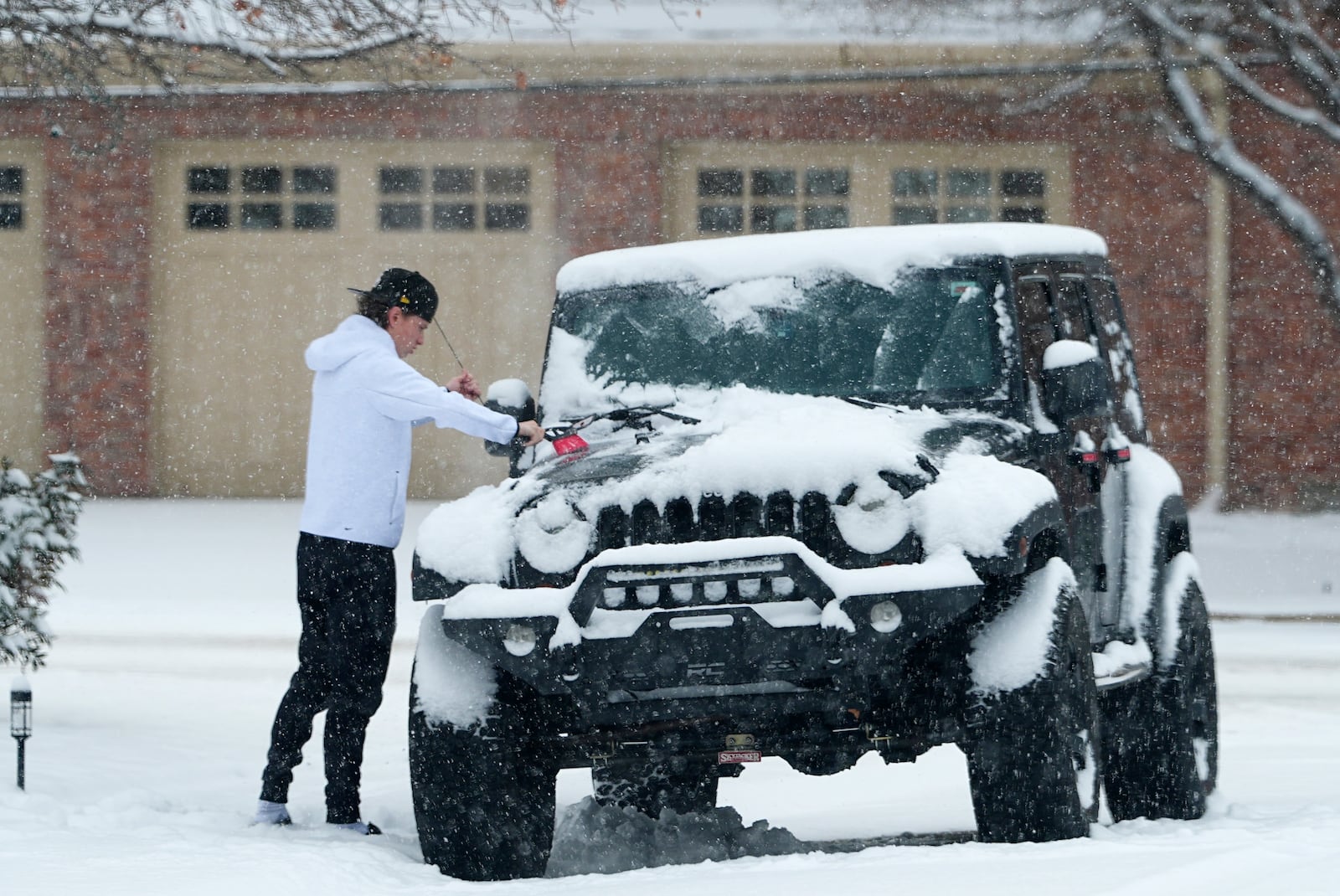 A motorist clears now off a four-wheel-drive vehicle before taking to the roads as a winter storm sweeps over the intermountain West and across the country Tuesday, Jan. 7, 2025, in Denver. (AP Photo/David Zalubowski)