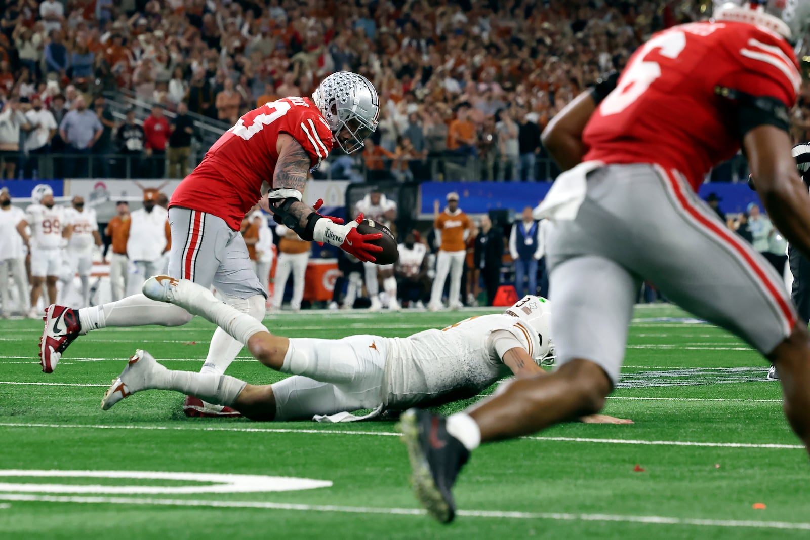 FILE _ Ohio State defensive end Jack Sawyer, left, scoops up a fumble by Texas quarterback Quinn Ewers, bottom, before returning it for a touchdown during the second half of the Cotton Bowl College Football Playoff semifinal game, Friday, Jan. 10, 2025, in Arlington, Texas. (AP Photo/Gareth Patterson, File)