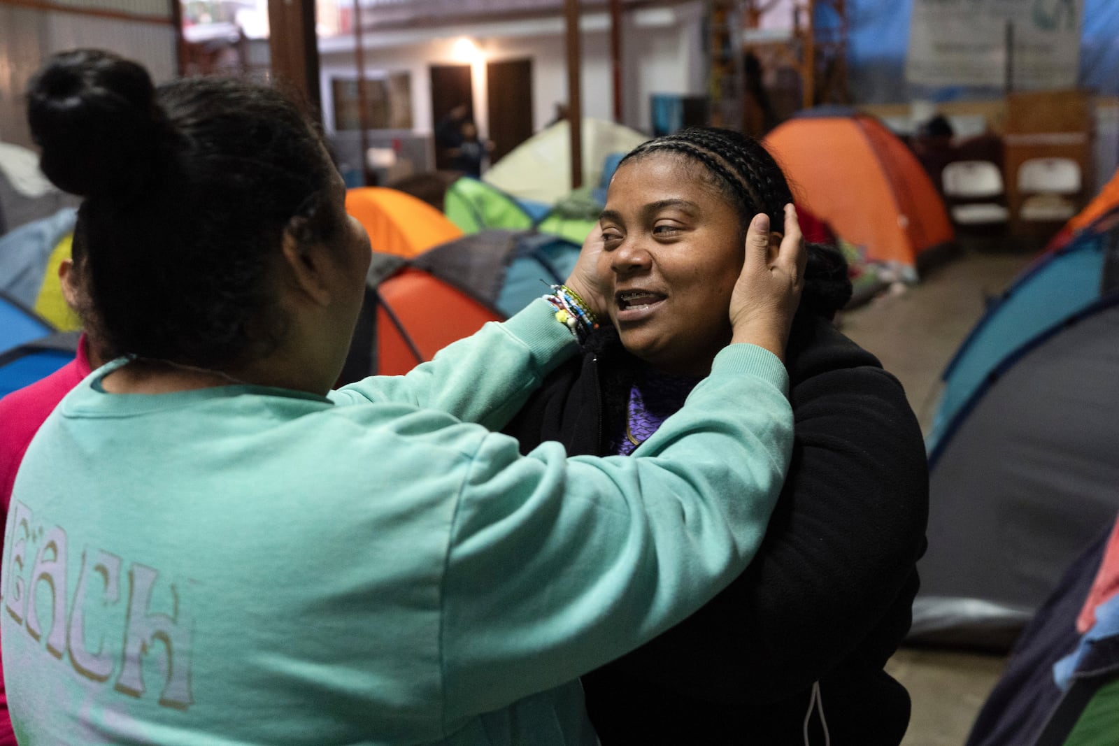 Margelis Rodriguez, right, of Venezuela, gets a hug from a friend at a migrant shelter where she is staying with her two children in Tijuana, Mexico, Wednesday, Feb. 5, 2025. (AP Photo/Gregory Bull)