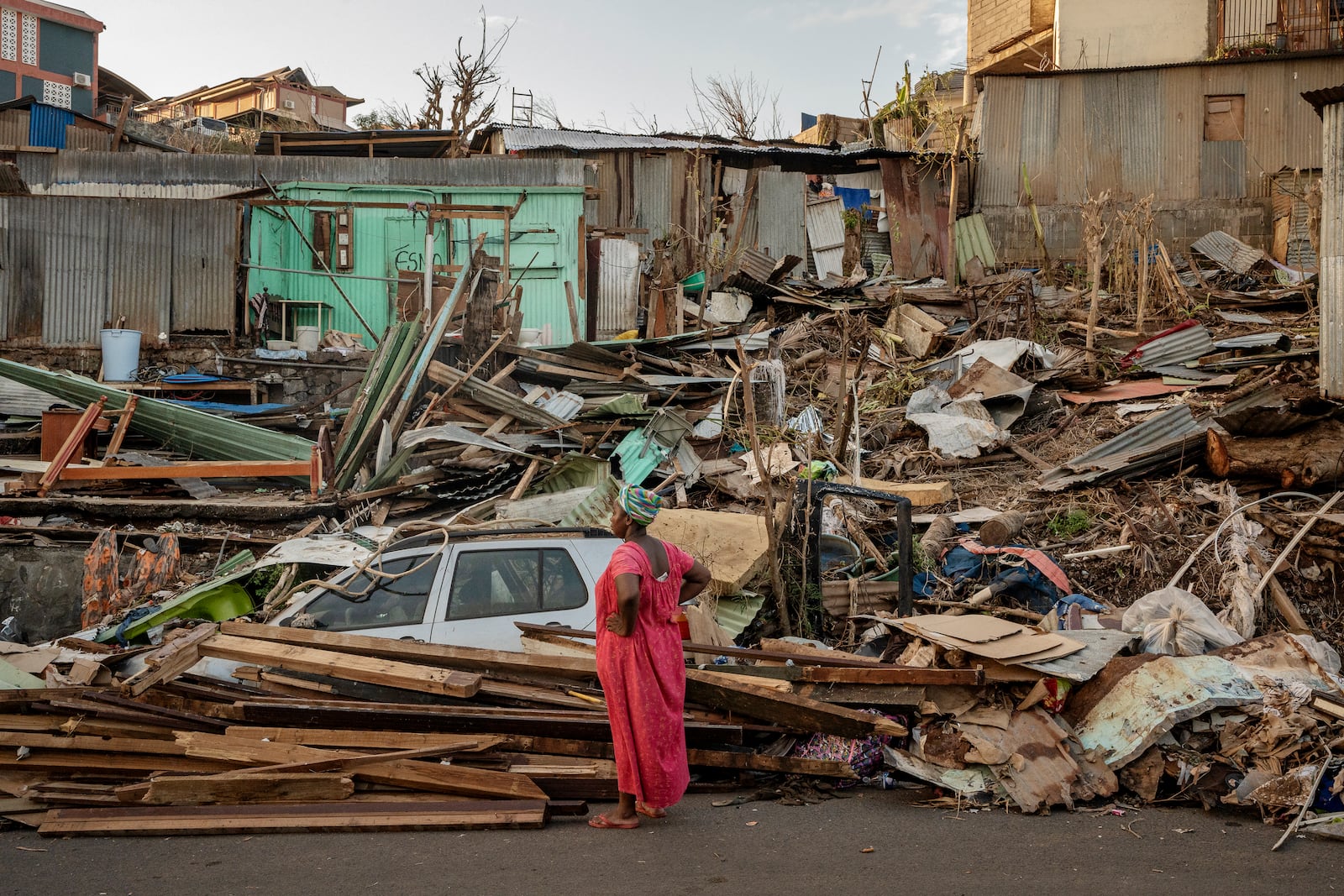 A woman looks at a destroyed home in Mamoudzou, Mayotte, Thursday, Dec. 19, 2024. (AP Photo/Adrienne Surprenant)