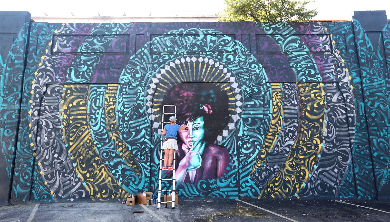 Tiffany Clark, founder of the Mural Machine, is creating a new mural at the entrance of the Oregon District in Dayton.  LISA POWELL / STAFF