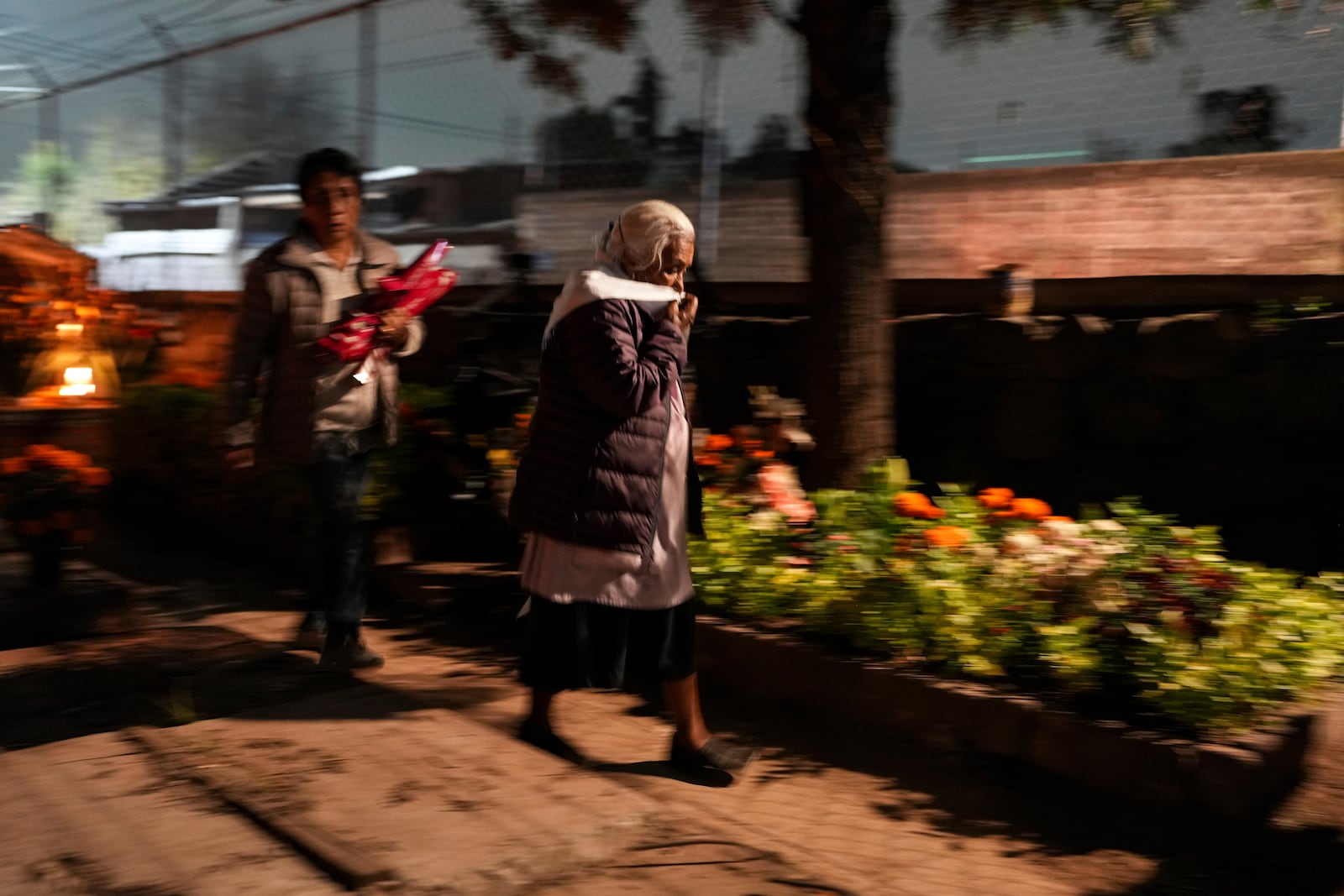 Women arrive at the cemetery to keep company with their dearly departed, as they celebrate Day of the Dead, at the San Gregorio Atlapulco on the outskirts of Mexico City, Friday, Nov. 1, 2024. (AP Photo/Moises Castillo)