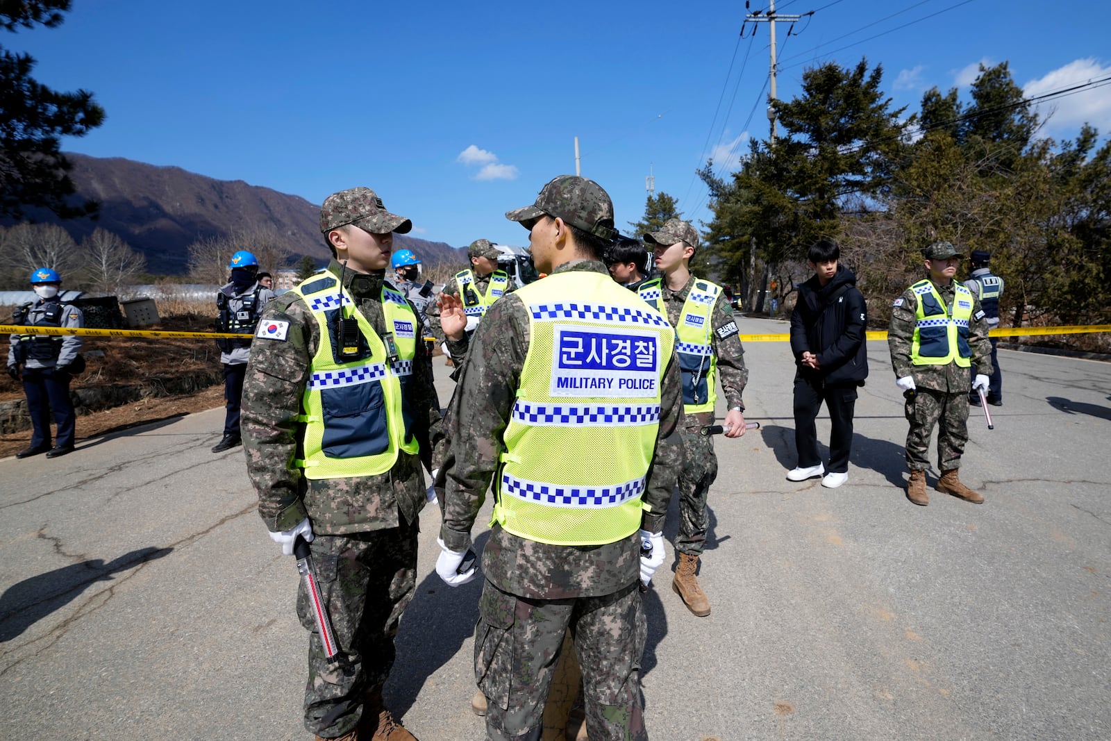 South Korean soldiers and police officers stand near the scene where a South Korean fighter jet accidentally dropped bombs on a civilian area during training, in Pocheon, South Korea, Thursday, March 6, 2025. (AP Photo/Lee Jin-man)