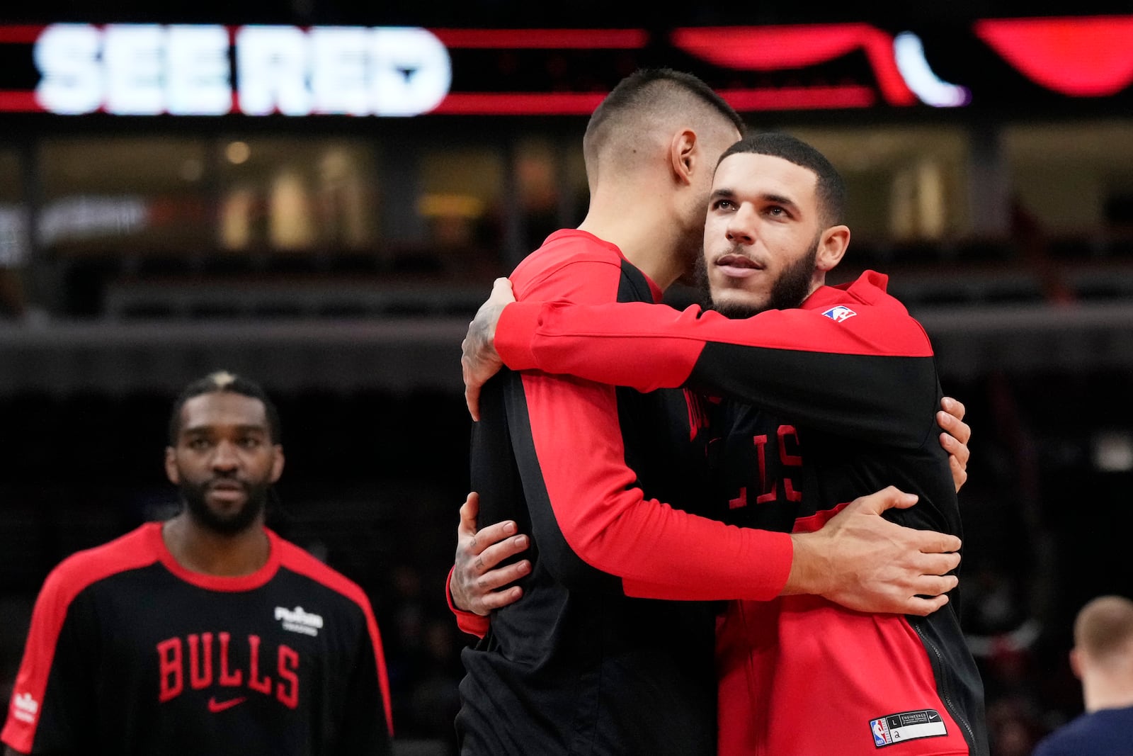 Chicago Bulls guard Lonzo Ball, right, hugs center Nikola Vucevic before an NBA preseason basketball game against the Minnesota Timberwolves in Chicago, Wednesday, Oct. 16, 2024. (AP Photo/Nam Y. Huh)