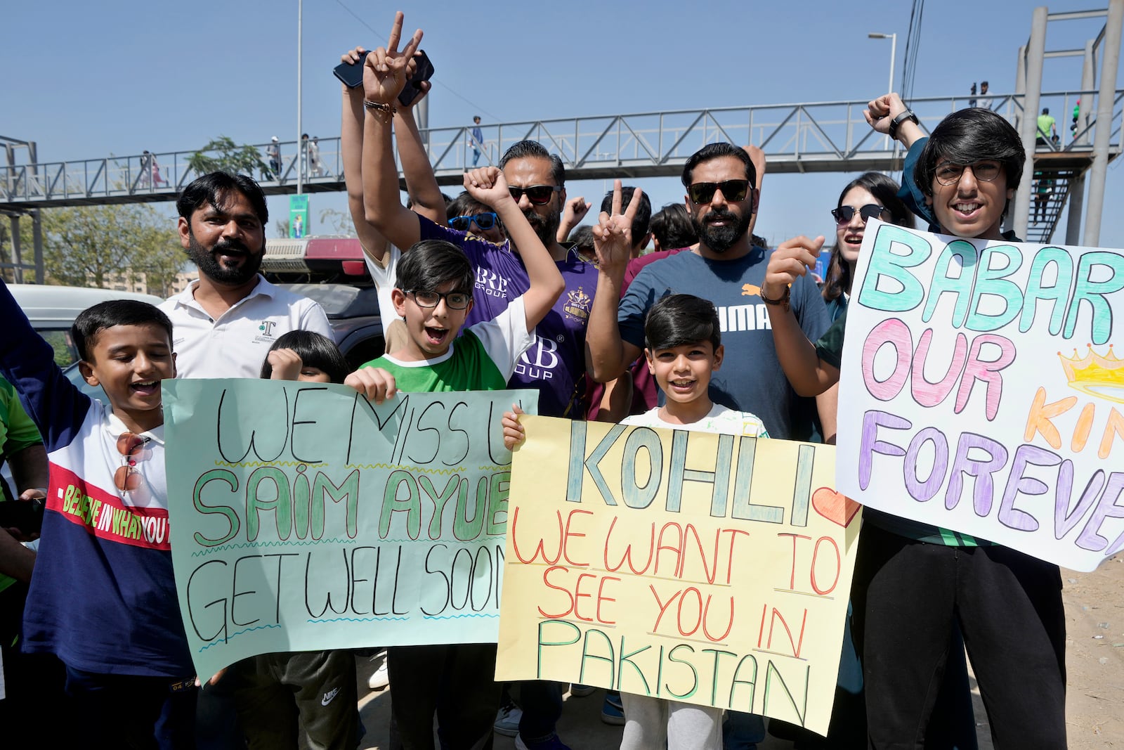 A fan holds a placard reading 'Kohli we want to see you in Pakistan' as he arrives with others at the National Bank Stadium for the ICC Champions Trophy cricket match between Pakistan and New Zealand, in Karachi, Pakistan, Feb. 19, 2025. (AP Photo/Fareed Khan)