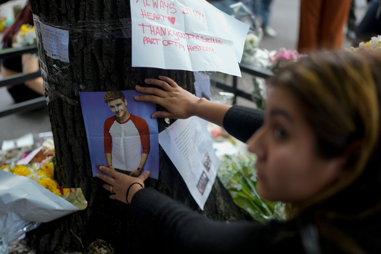 A fan of former One Direction singer Liam places a photo of him on a tree outside the hotel where he was found dead after falling from a balcony the previous day in Buenos Aires, Argentina, Thursday, Oct. 17, 2024. (AP Photo/Natacha Pisarenko)