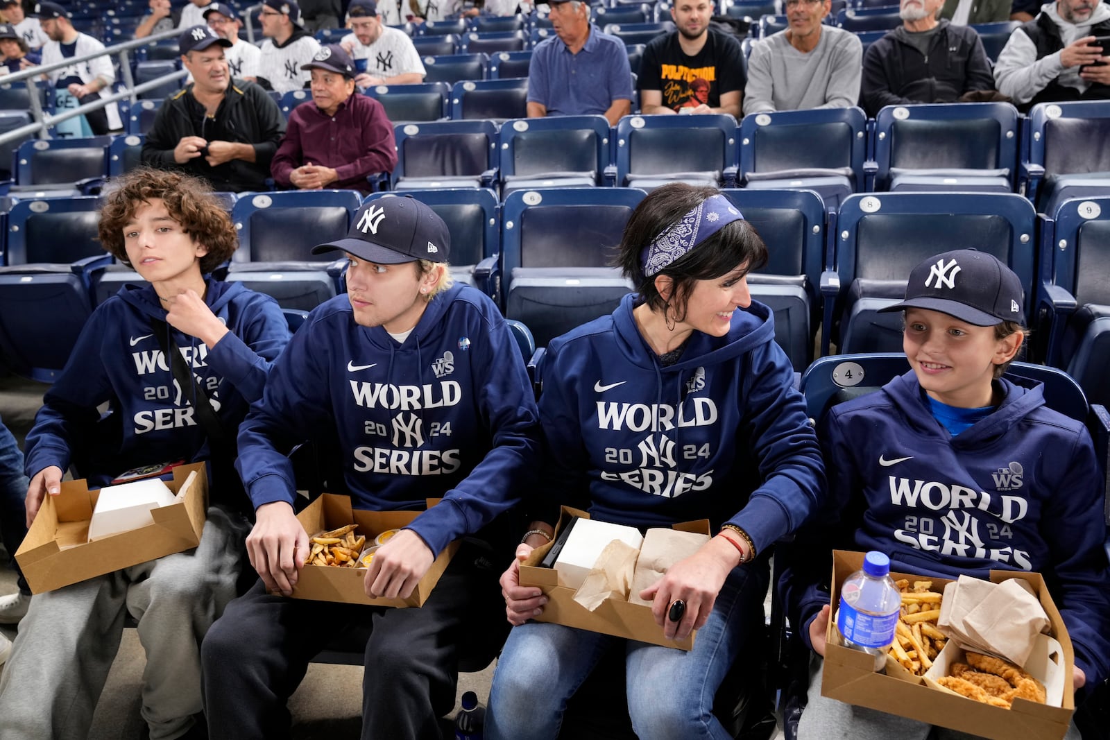 From right to left, Everett Teel-Young sits with his mother, Jacquelyn Teel and brothers Calvin and Trevor, during batting practice before Game 5 of the baseball World Series between the Los Angeles Dodgers and New York Yankees, Wednesday, Oct. 30, 2024, in New York. The family was given tickets from the New York Yankees to sit in the section where fans were ejected during Game 4 after interfering with Los Angeles Dodgers' Mookie Betts as he made a catch.(AP Photo/Seth Wenig)