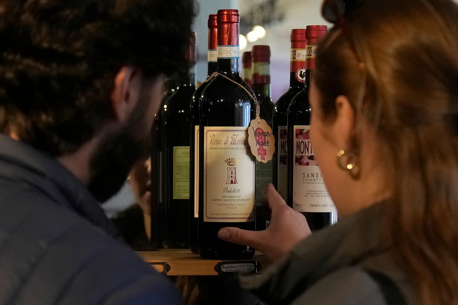 Carlos Olivares, left, and Morgan Berry look at a bottle of Padelletti Rosso di Montalcino Riserva, from Italy, at DECANTsf Bottle Shop and Bar in San Francisco, Thursday, March 13, 2025. (AP Photo/Jeff Chiu)