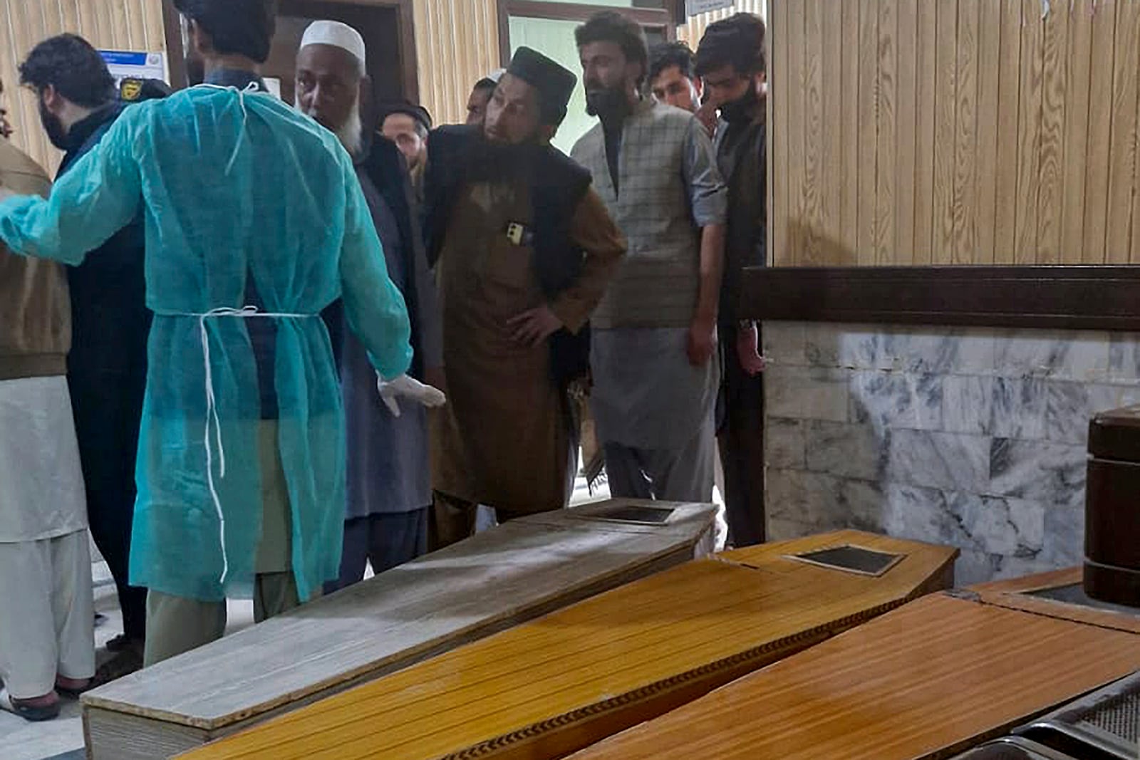 People stand next to the caskets of the victims of bomb explosion in a mosque within a pro-Taliban seminary, at a hospital in Nowshera, a town in the Pakistan's northwestern Khyber Pakhtunkhwa province, Friday, Feb. 28, 2025. (AP Photo/Riaz Khan)