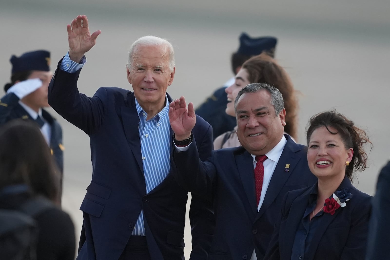 U.S. President Joe Biden, left, Peru's Prime Minister Gustavo Adrianzen, center, and US Ambassador to Peru Stephanie Syptak-Ramnath wave on the airport tarmac ahead of the Asia-Pacific Economic Cooperation (APEC) summit, in Lima, Peru, Thursday, Nov. 14, 2024. (AP Photo/Guadalupe Pardo)