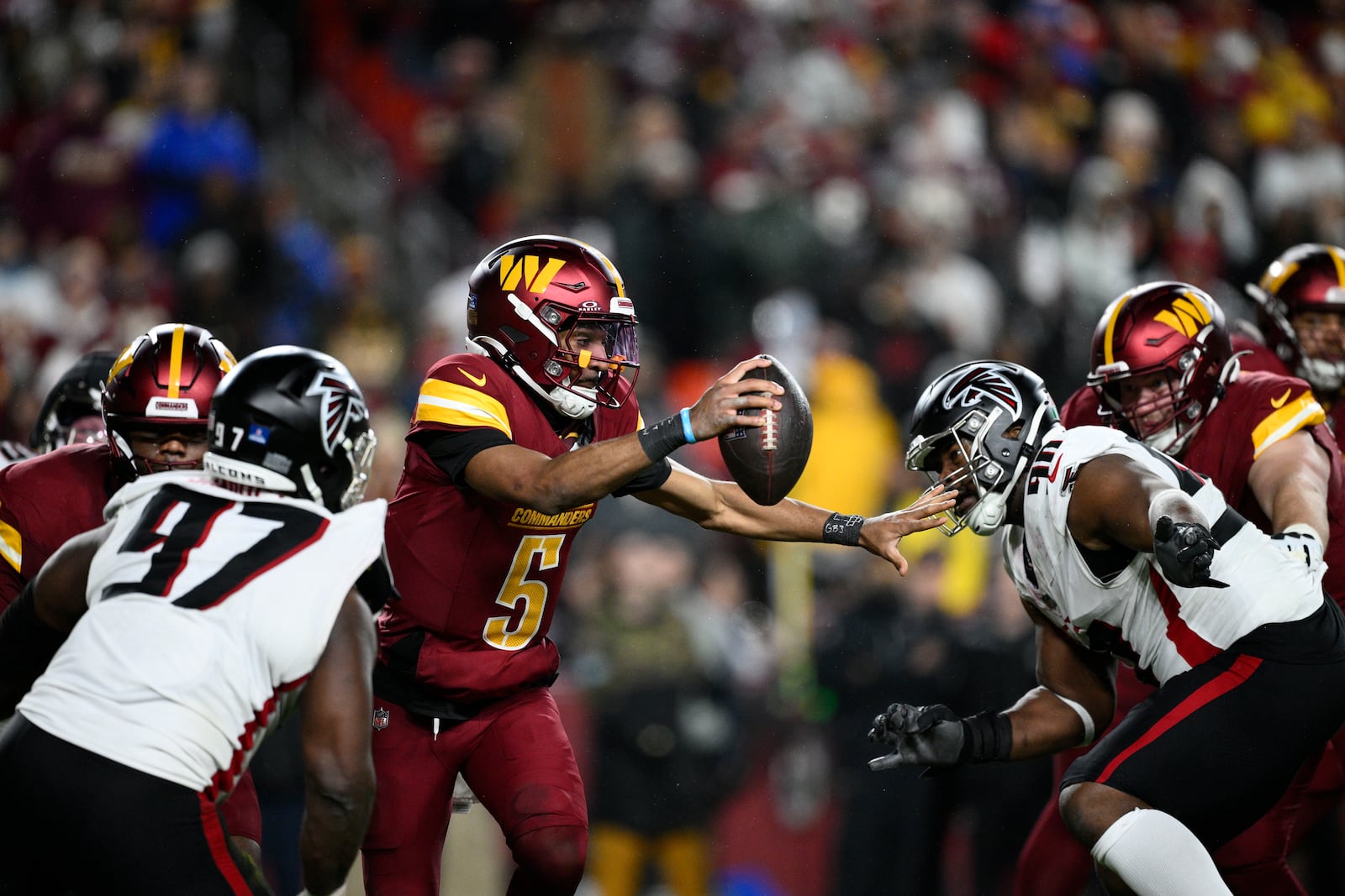 Washington Commanders quarterback Jayden Daniels (5) scrambles between Atlanta Falcons defensive end Grady Jarrett (97) and defensive tackle David Onyemata during the second half of an NFL football game, Sunday, Dec. 29, 2024, in Landover, Md. (AP Photo/Nick Wass)