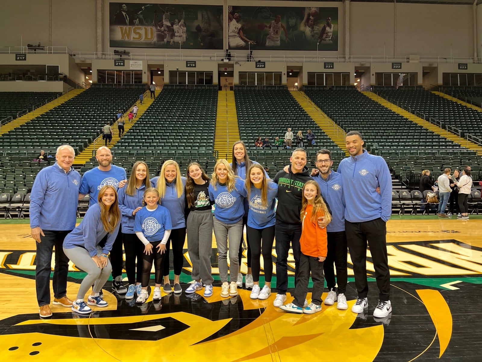 Wright State freshman guard Ellie Magestro Kennedy (fifth person from right) surrounded by her family, the Raiders coaching staff and (far left) Jeff Kolok, CEO of SLAMT1D, and his daughter JoJo (in front of him.) Alex Underwood/Wright State Athletics photo