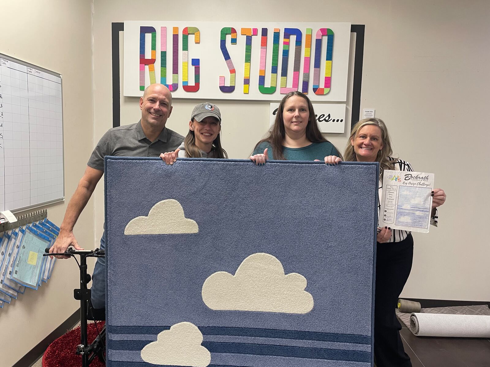 Bockrath Flooring and Rugs, a Dayton area business since 1959, has partnered with We Care Arts to bring an artist’s work on paper to life through a rug. Pictured left to right is Doug Bockrath, Jess Perrine, Abbie Kingham and Erin Bockrath.