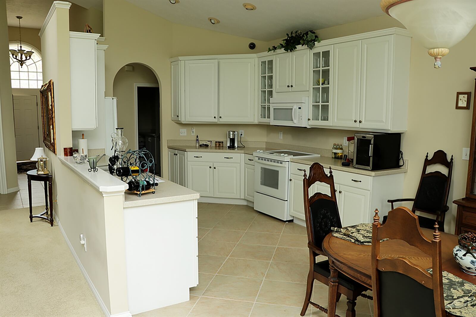 The dining area and kitchen area flow together, creating a galley-style kitchen. Beveled countertops complement the 42-inch custom white cabinetry, some of which have glass fronts. CONTRIBUTED PHOTO BY KATHY TYLER