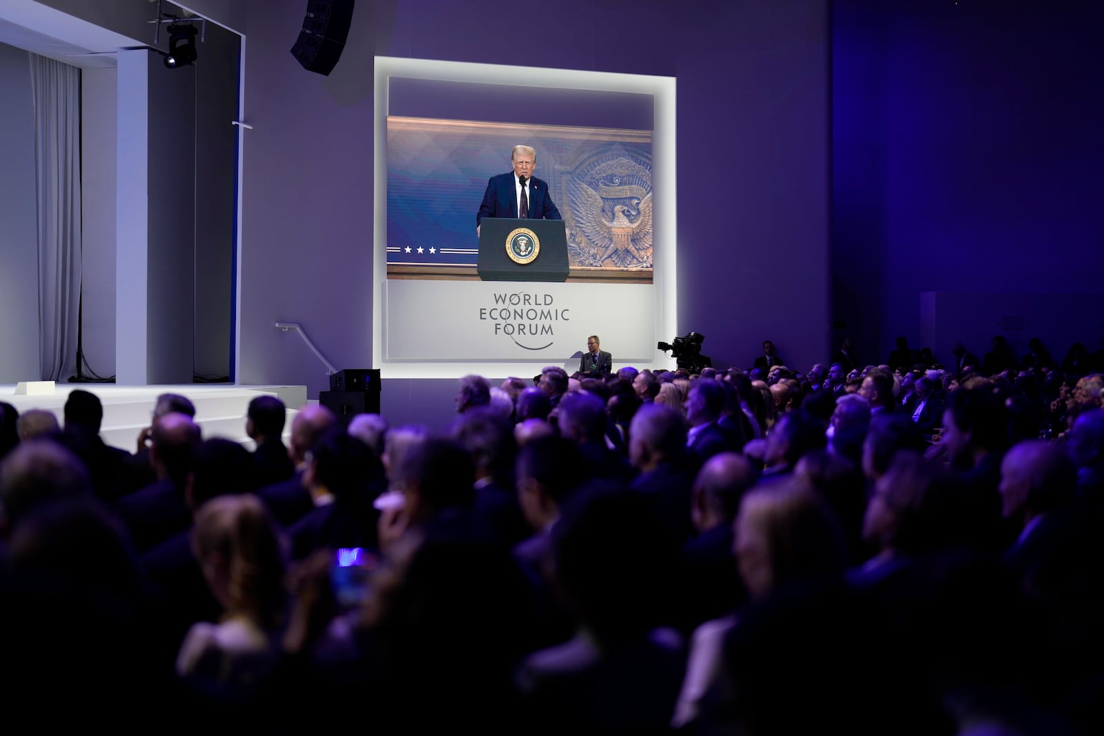 People follow a virtual speech of U.S. president Donald Trump at the Annual Meeting of World Economic Forum in Davos, Switzerland, Thursday, Jan. 23, 2025. (AP Photo/Markus Schreiber)