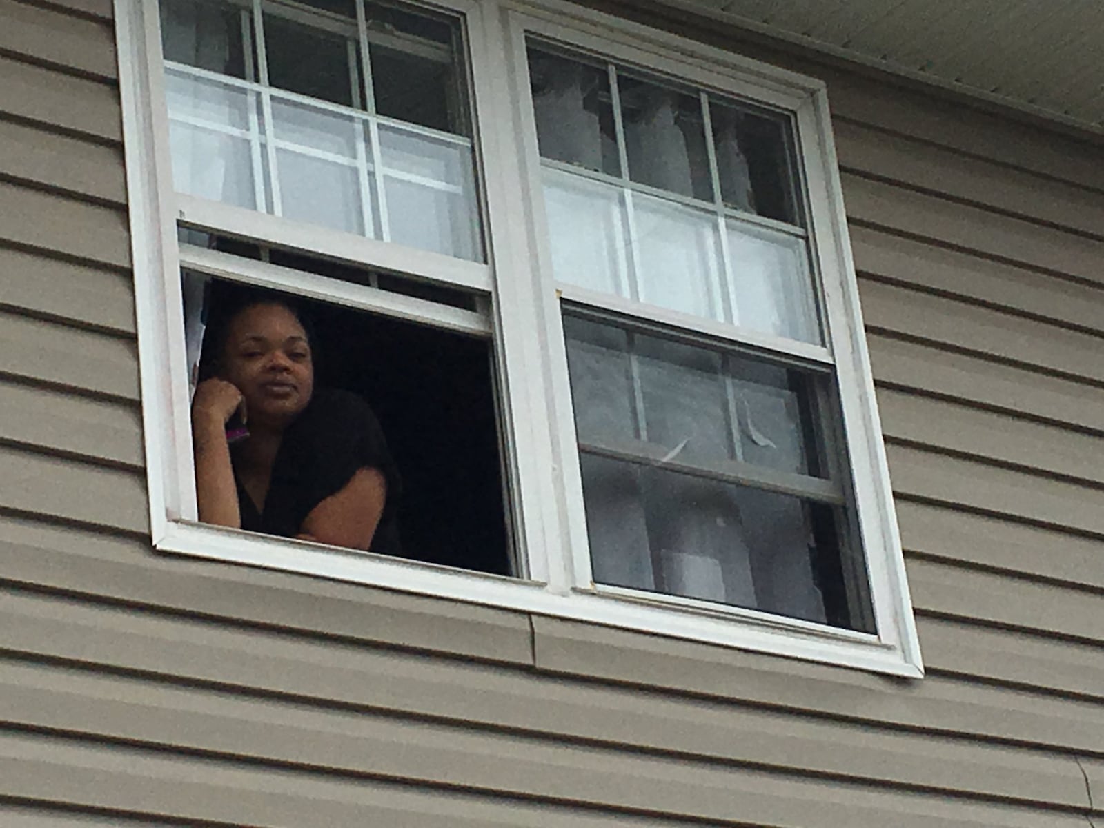 Destynee Gregory talks to a reporter from her second floor window at Meadowlark Apartments in Trotwood. She has two preschool age children, including one with a weakened immune system.