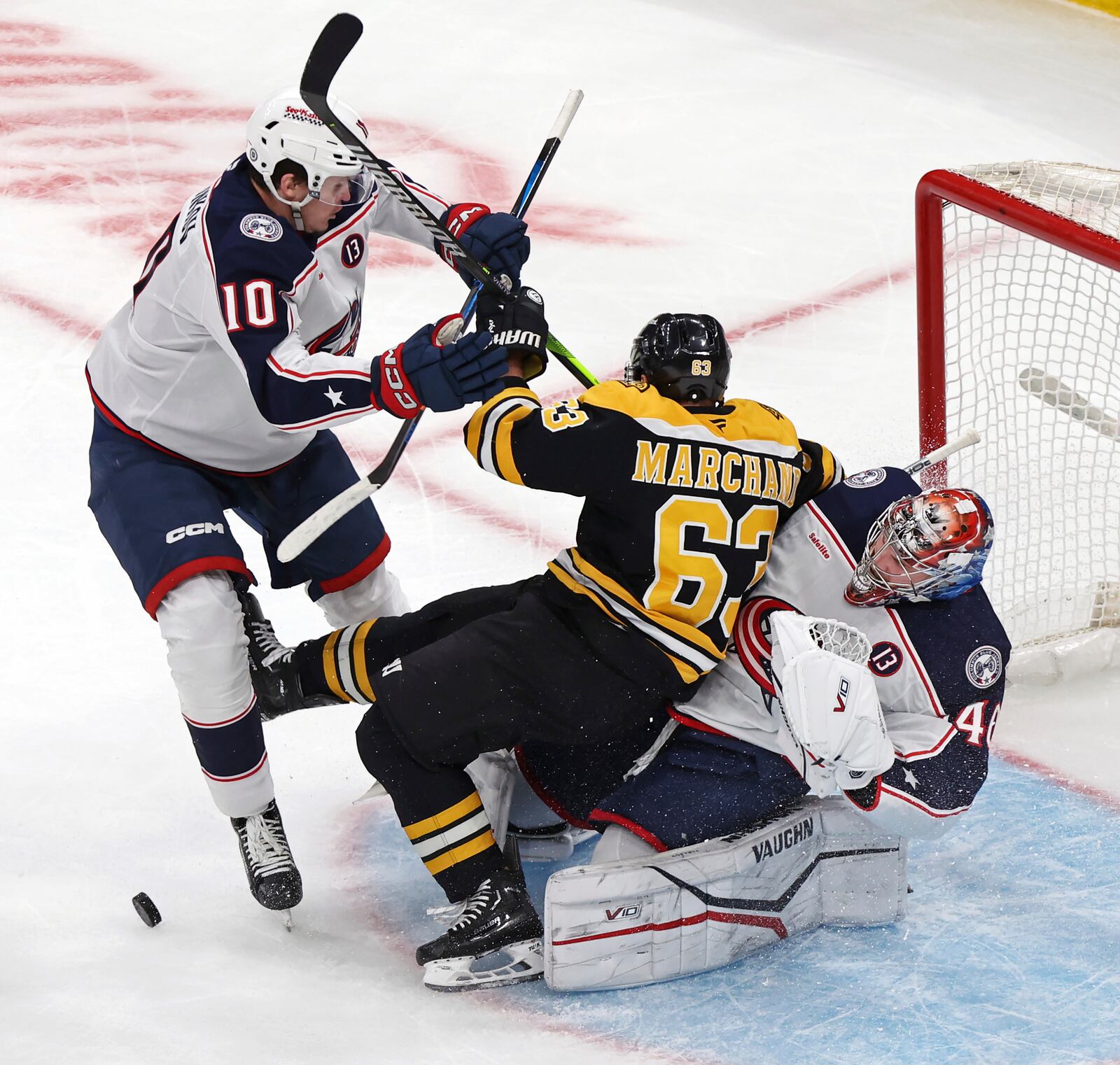 Boston Bruins forward Brad Marchand (63) crashes into Columbus Blue Jackets goalie Daniil Tarasov, right, as Blue Jackets forward Dmitri Voronkov (10) looks on during the first period of an NHL hockey game on Saturday, Dec. 28, 2024 in Boston. (AP Photo/Jim Davis)