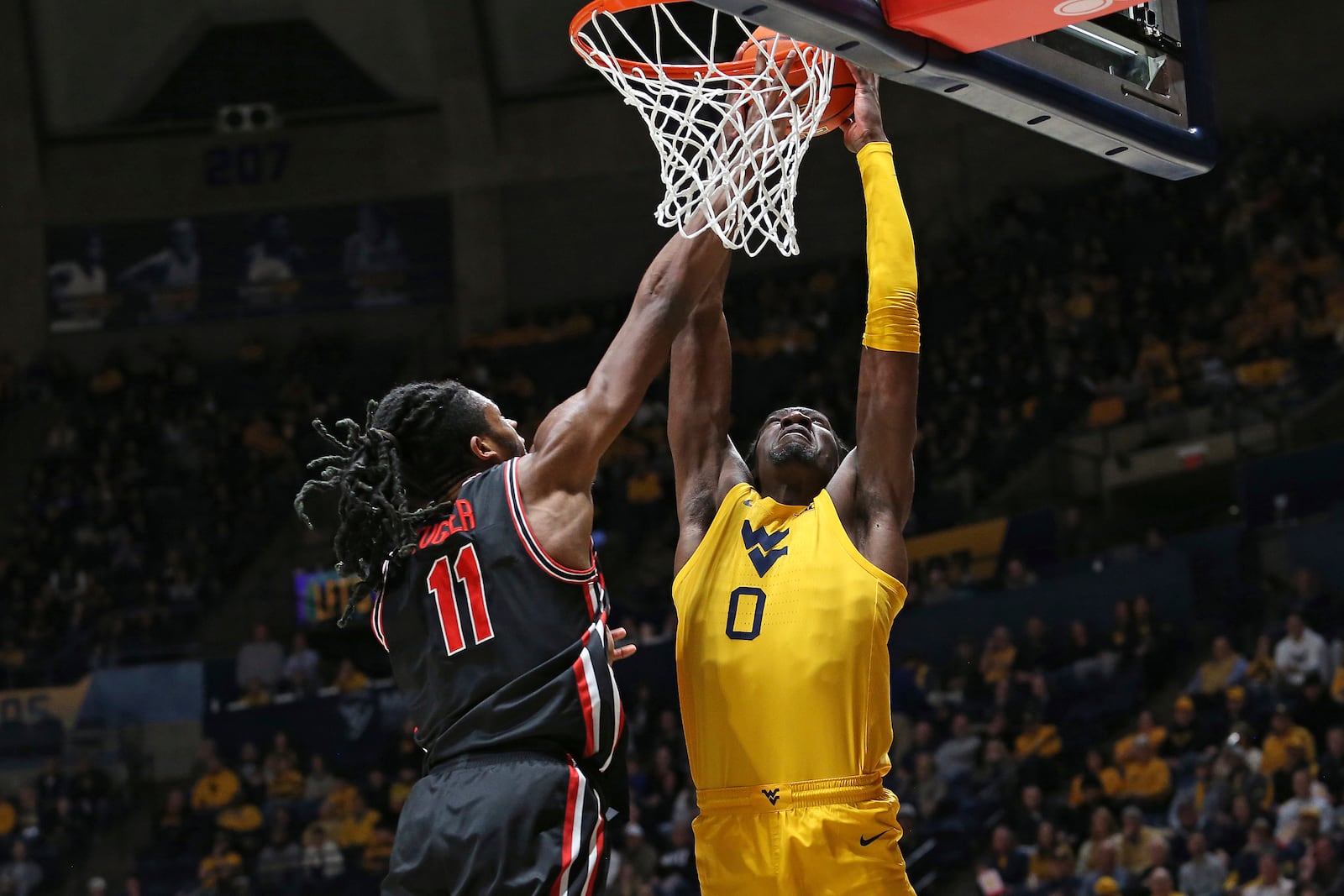 West Virginia center Eduardo Andre (0) is defended by Houston forward Joseph Tugler (11) during the first half of an NCAA college basketball game, Wednesday, Jan. 29, 2025, in Morgantown, W.Va. (AP Photo/Kathleen Batten)