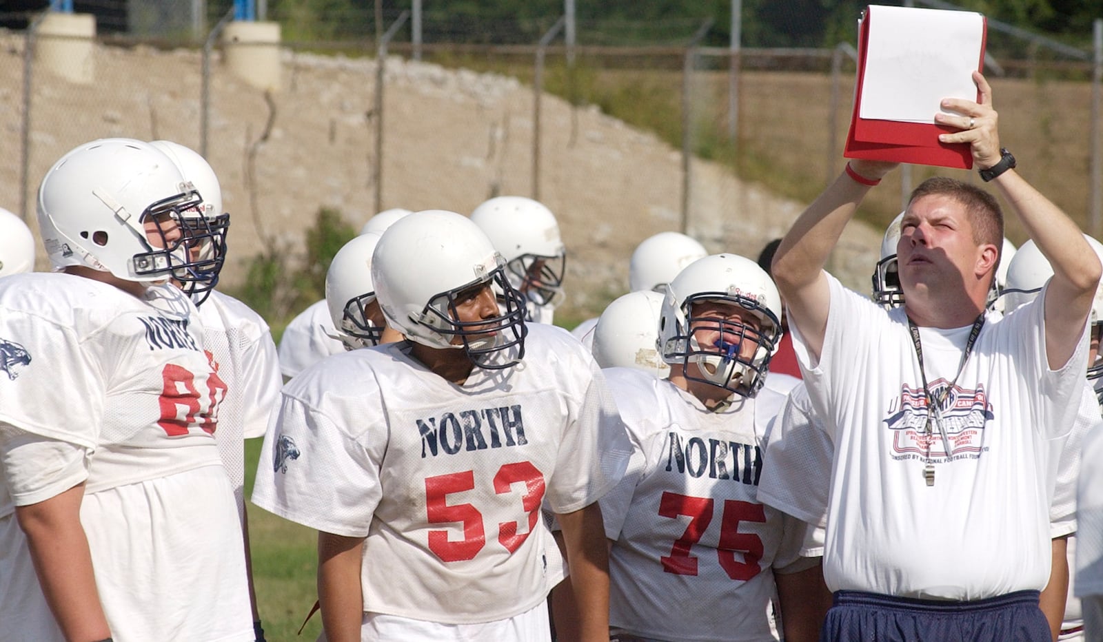 North's head coach John Rommel holds up a playbook during practice for their opening game Thursday night at North High School in 2005. Teesha McClam/News-Sun