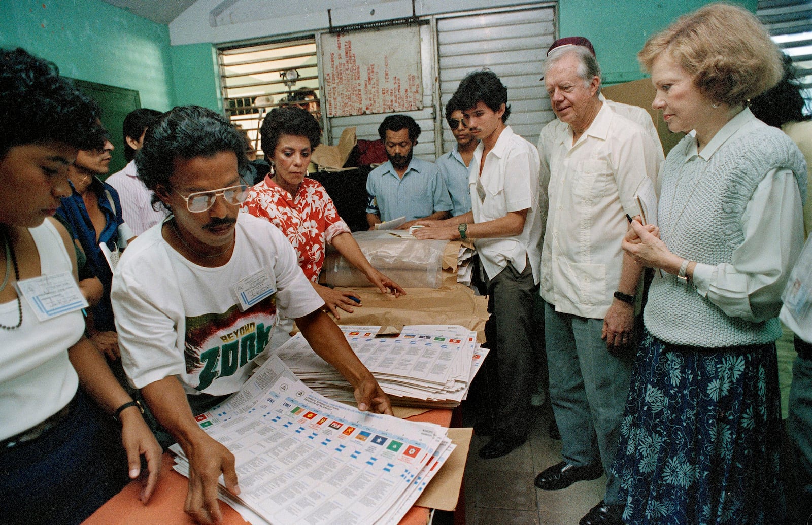 FILE - Former U.S. President Jimmy Carter and his wife, Rosalynn, right, watch election workers prepare ballots at a polling station in Managua, Nicaragua, Feb. 25, 1990. (AP Photo/J. Scott Applewhite, File)