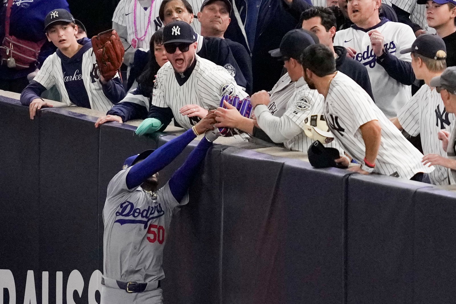 Fans interfere with a foul ball caught by Los Angeles Dodgers right fielder Mookie Betts during the first inning in Game 4 of the baseball World Series against the New York Yankees, Tuesday, Oct. 29, 2024, in New York. (AP Photo/Ashley Landis)