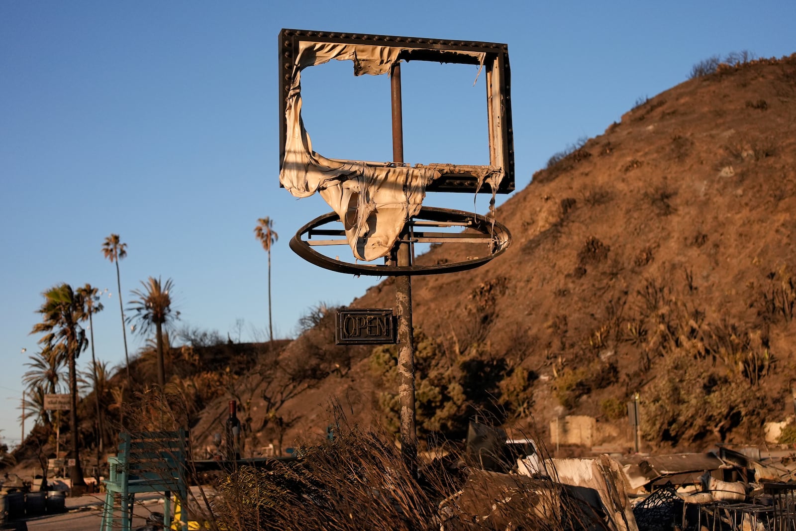 A sign is left behind, damaged by the Palisades Fire Monday, Jan. 13, 2025 in Malibu, Calif. (AP Photo/John Locher)