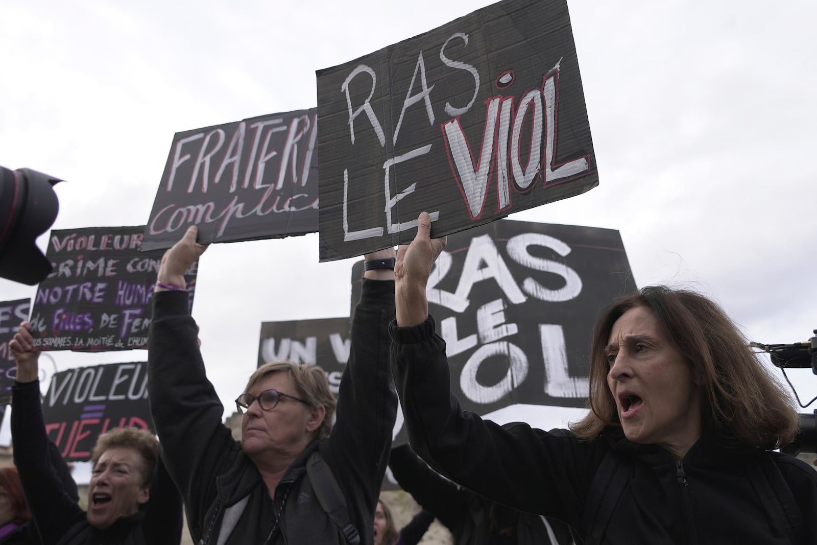 Women demonstrate, one with a placard reading "Stop raping", to mark the International Day for the Elimination of Violence against Women, as the trial of dozens of men accused of raping Gisele Pelicot while she was drugged and rendered unconscious by her husband goes on, Monday, Nov. 25, 2024 in Avignon, southern France. (AP Photo/John Leicester)