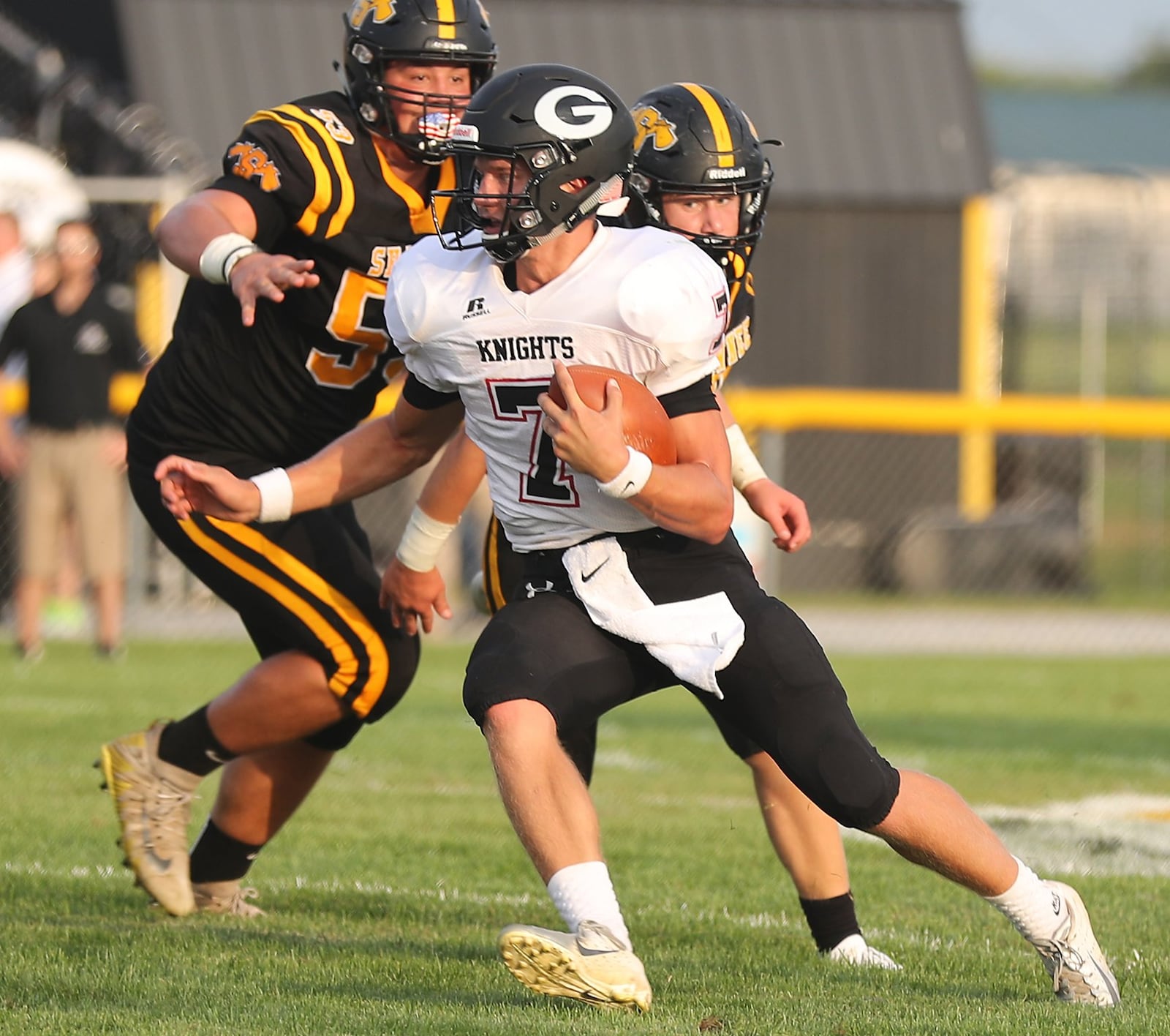 cGreenon quarterback Cade Rice scrambles out of the pocket to avoid being sacked by Shawnee’s Josh Lange, left, and Rudy Scanlon during Friday’s season opener. BILL LACKEY/STAFF