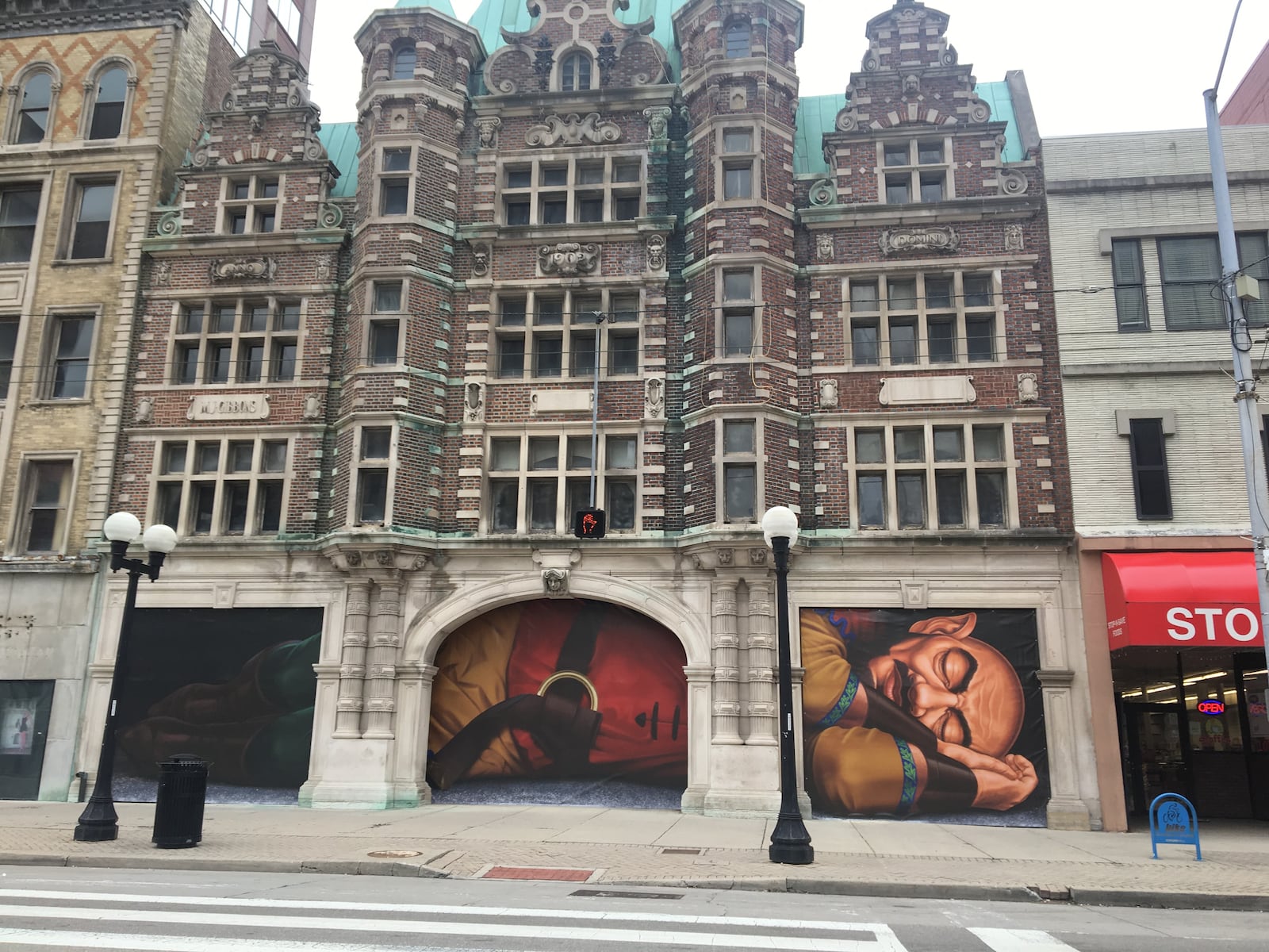 Vinyl posters depicting a sleeping giant are covering the north entrance of the Dayton Arcade. The coverings feature a 40-foot-long giant, who is a metaphor for the Arcades long sleep and eventual awakening, according to Cross Street Partners, the firm that is working to redevelop the arcade. CORNELIUS FROLIK/STAFF