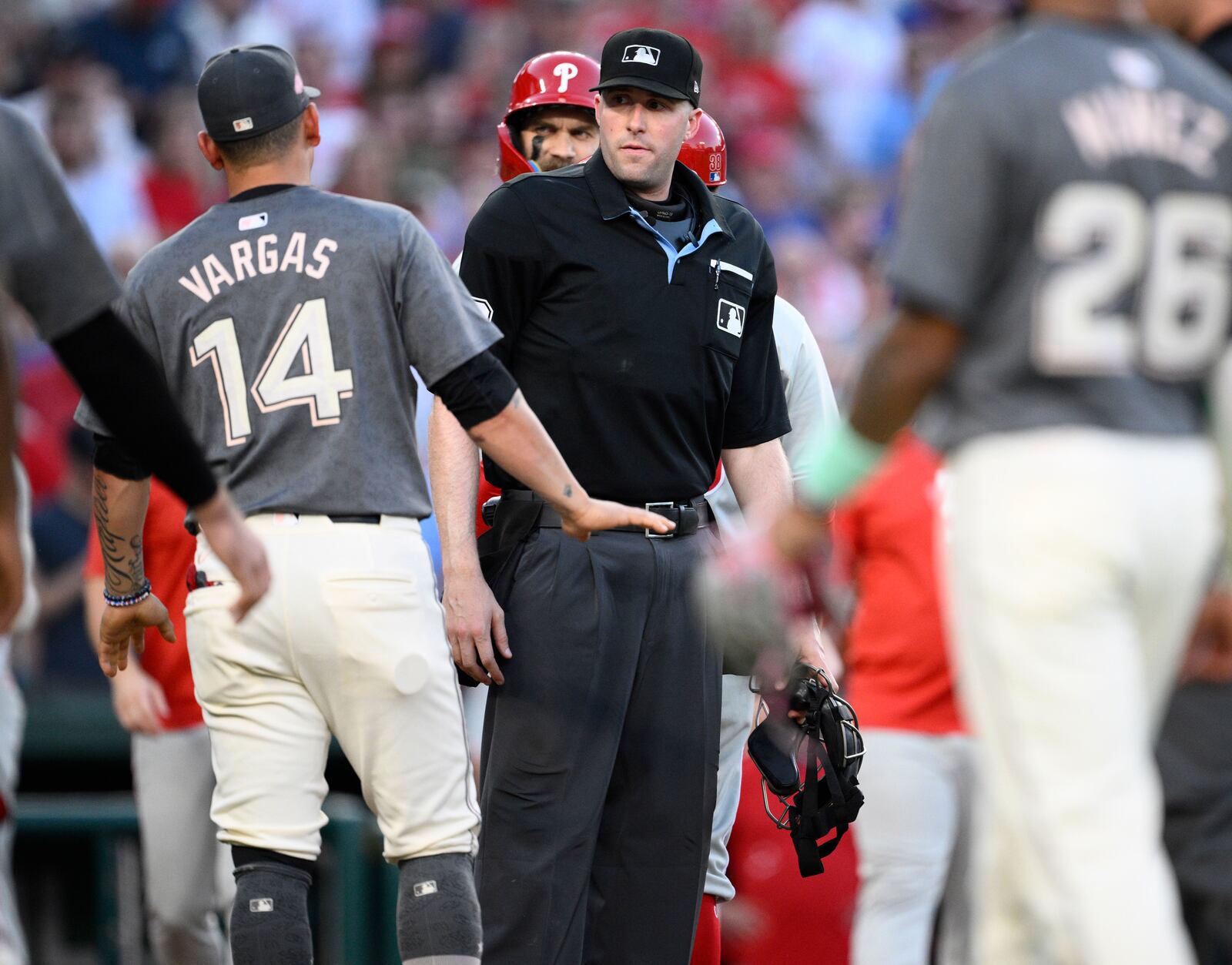 Home plate umpire Nic Lentz, center, looks on as Washington Nationals' Ildemaro Vargas (14) and Philadelphia Phillies' Bryce Harper, center back, and others come onto the field as dugouts cleared during the eighth inning of a baseball game, Saturday, Sept. 28, 2024, in Washington. (AP Photo/Nick Wass)