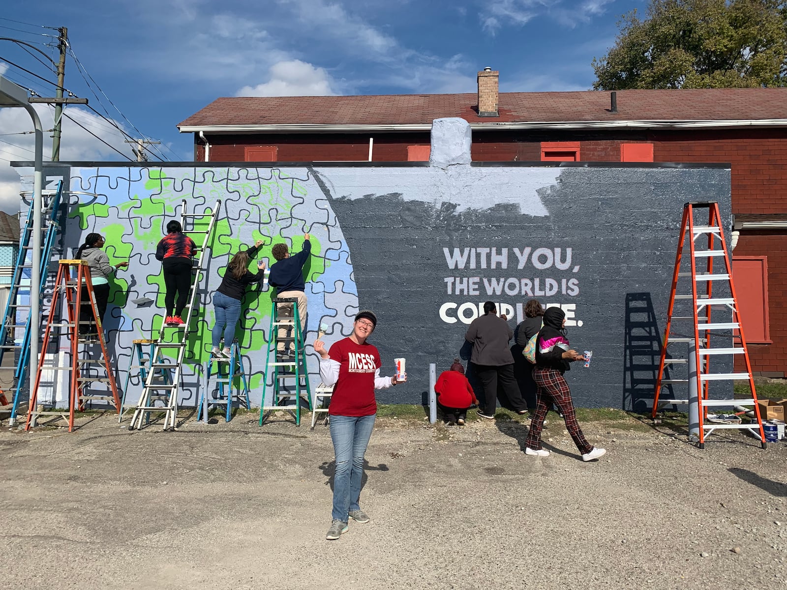 File - Local students and members of the Montgomery County Prevention Coalition in 2022 working on the first of four suicide prevention murals. The first completed mural is located in Old North Dayton at 2232 North Main St. at corner of Main and Fairview. It started as a 36-foot blank purple wall that, with 60 volunteers and an artist with a vision, shared the message, “With you, the world is complete.” COURTESY OF THE MONTGOMERY COUNTY PREVENTION COALITION