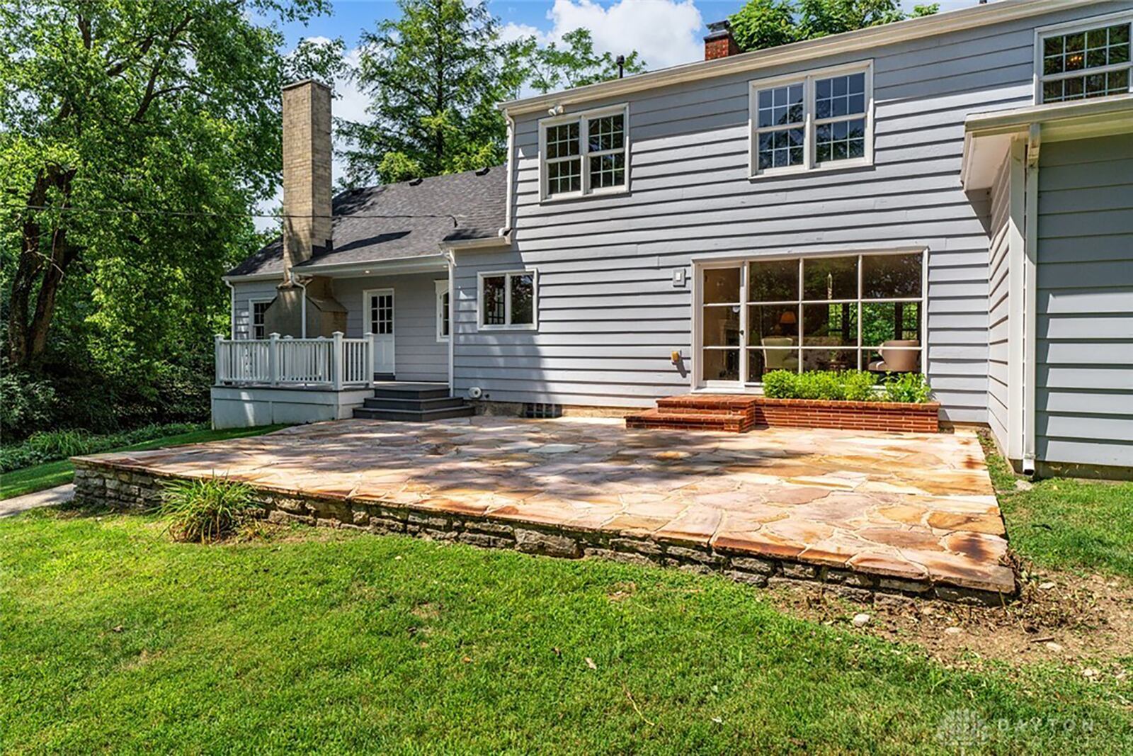 The rear of the home has a stone paver patio and wood deck and overlooks a tree lined back yard.