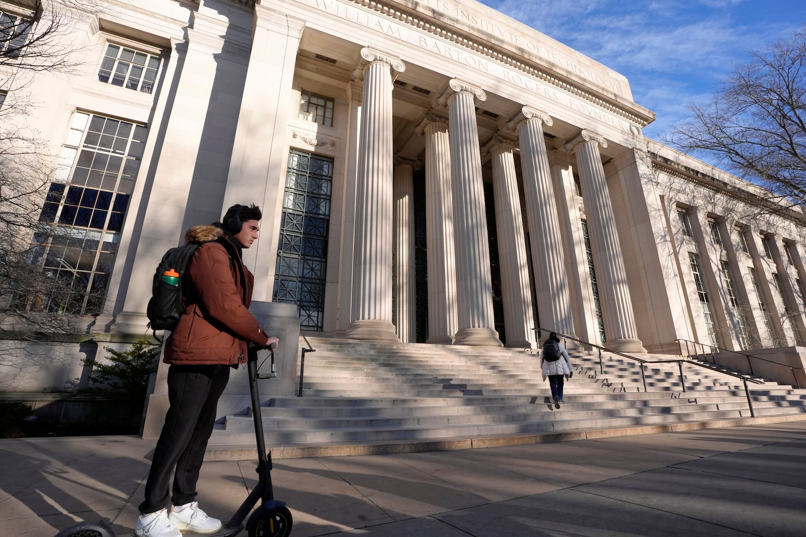 A person rides a scooter, Tuesday, Dec. 17, 2024, near an entrance to Massachusetts Institute of Technology in Cambridge, Mass. (AP Photo/Steven Senne)