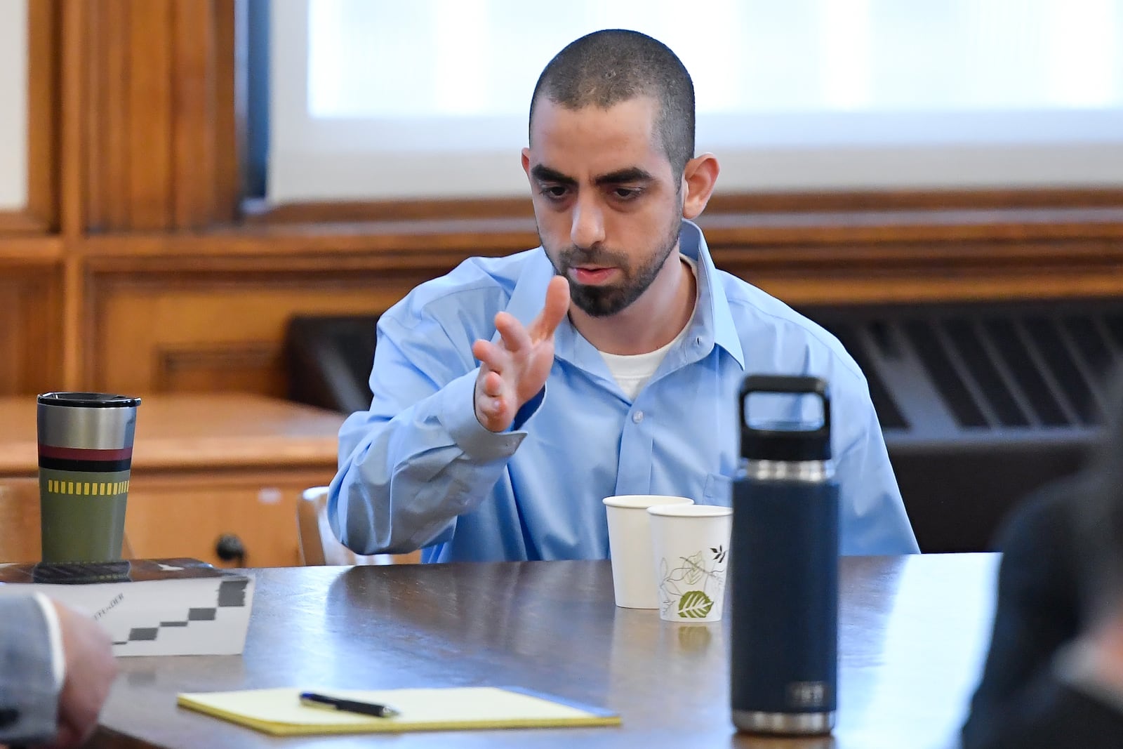 Hadi Matar, right, charged with severely injuring author Salman Rushdie in a 2022 knife attack, speaks to his defense team in Chautauqua County court in Mayville, N.Y., Monday, Feb. 10, 2025. (AP Photo/Adrian Kraus)