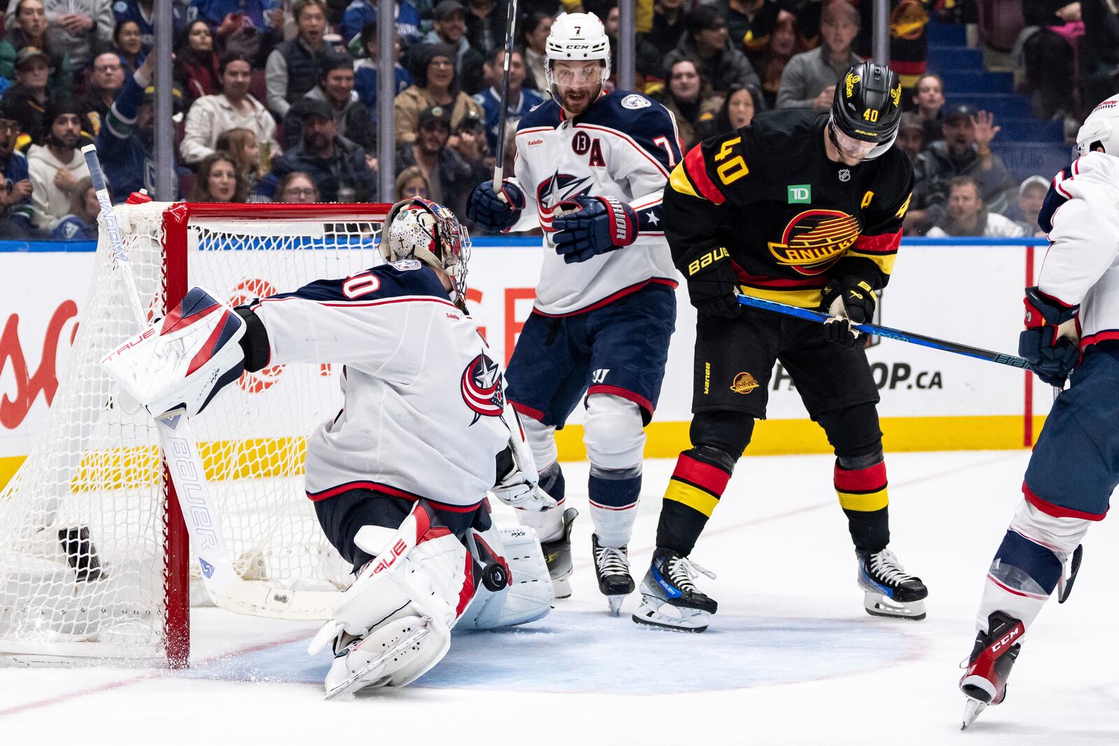 Columbus Blue Jackets goaltender Elvis Merzlikins (90) stops the puck as Sean Kuraly (7) and Vancouver Canucks' Elias Pettersson (40) watch during the third period of an NHL hockey game in Vancouver, British Columbia, Friday, Dec. 6, 2024. (Ethan Cairns/The Canadian Press via AP)