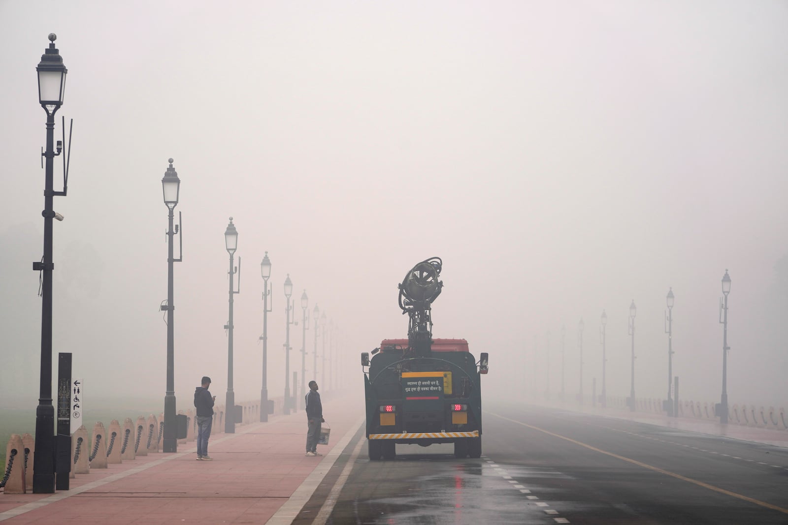 A Delhi government vehicle sprinkles water to control air pollution amidst thick Layer of smog in New Delhi, India, Monday, Nov. 18, 2024. (AP Photo/Manish Swarup)