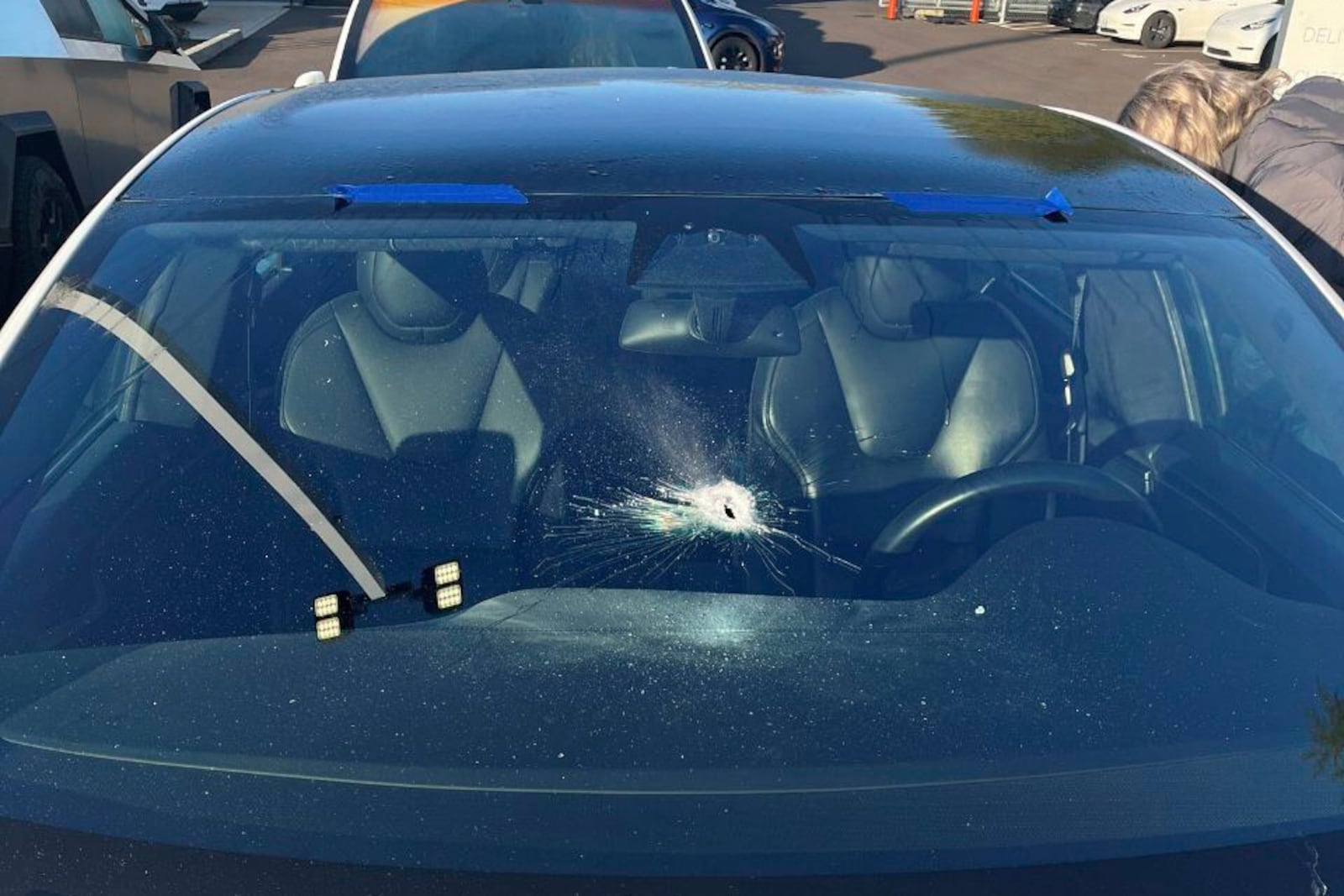 This photo released by the Tigard Police Department, shows a vehicle with a damaged windscreen outside of a Tesla dealership, Thursday, March 6, 2025, in Tigard. Oreg. (Tigard Police Department via AP)