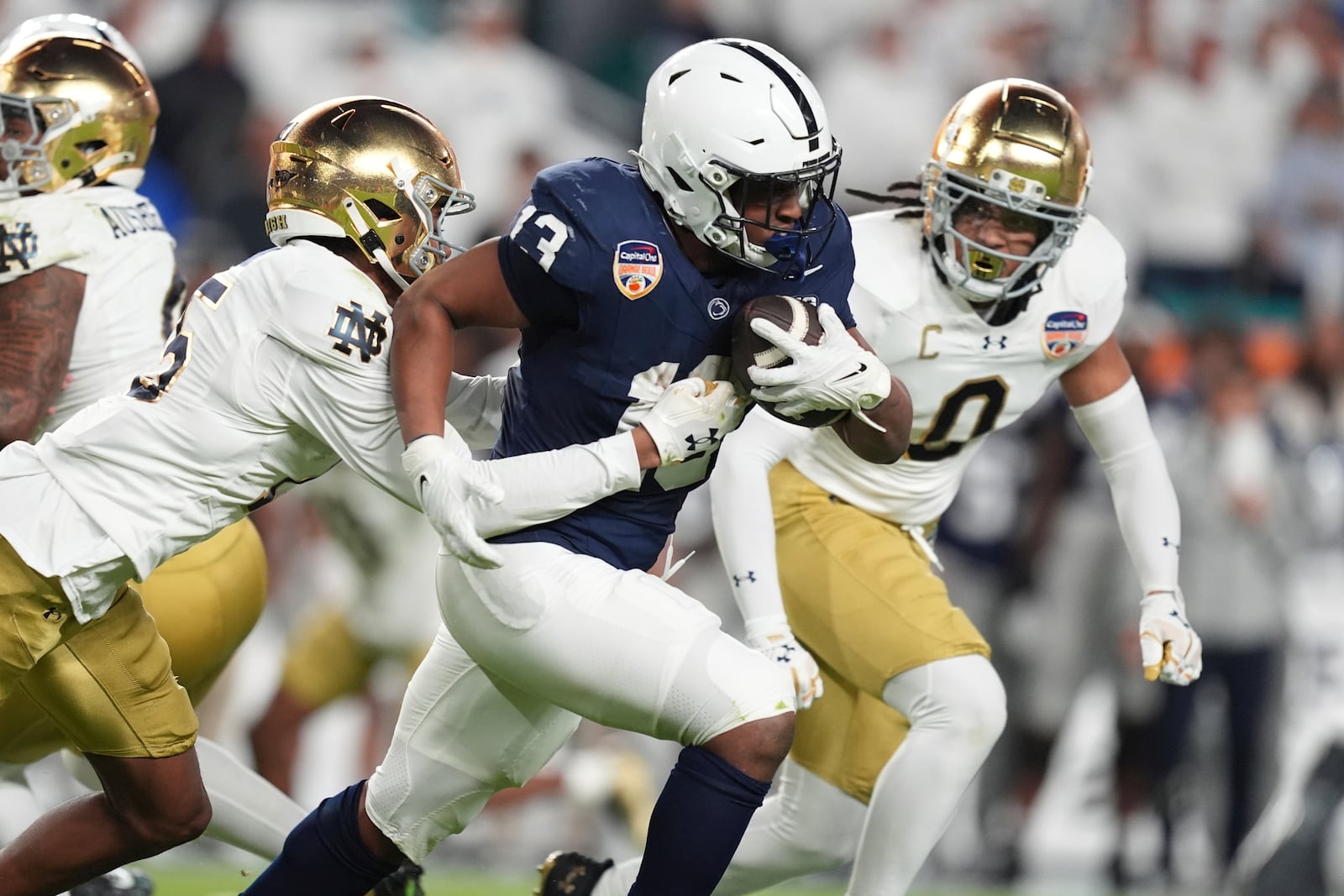 Notre Dame cornerback Leonard Moore (15) grabs Penn State running back Kaytron Allen (13) during the first half of the Orange Bowl NCAA College Football Playoff semifinal game, Thursday, Jan. 9, 2025, in Miami Gardens, Fla. (AP Photo/Rebecca Blackwell)