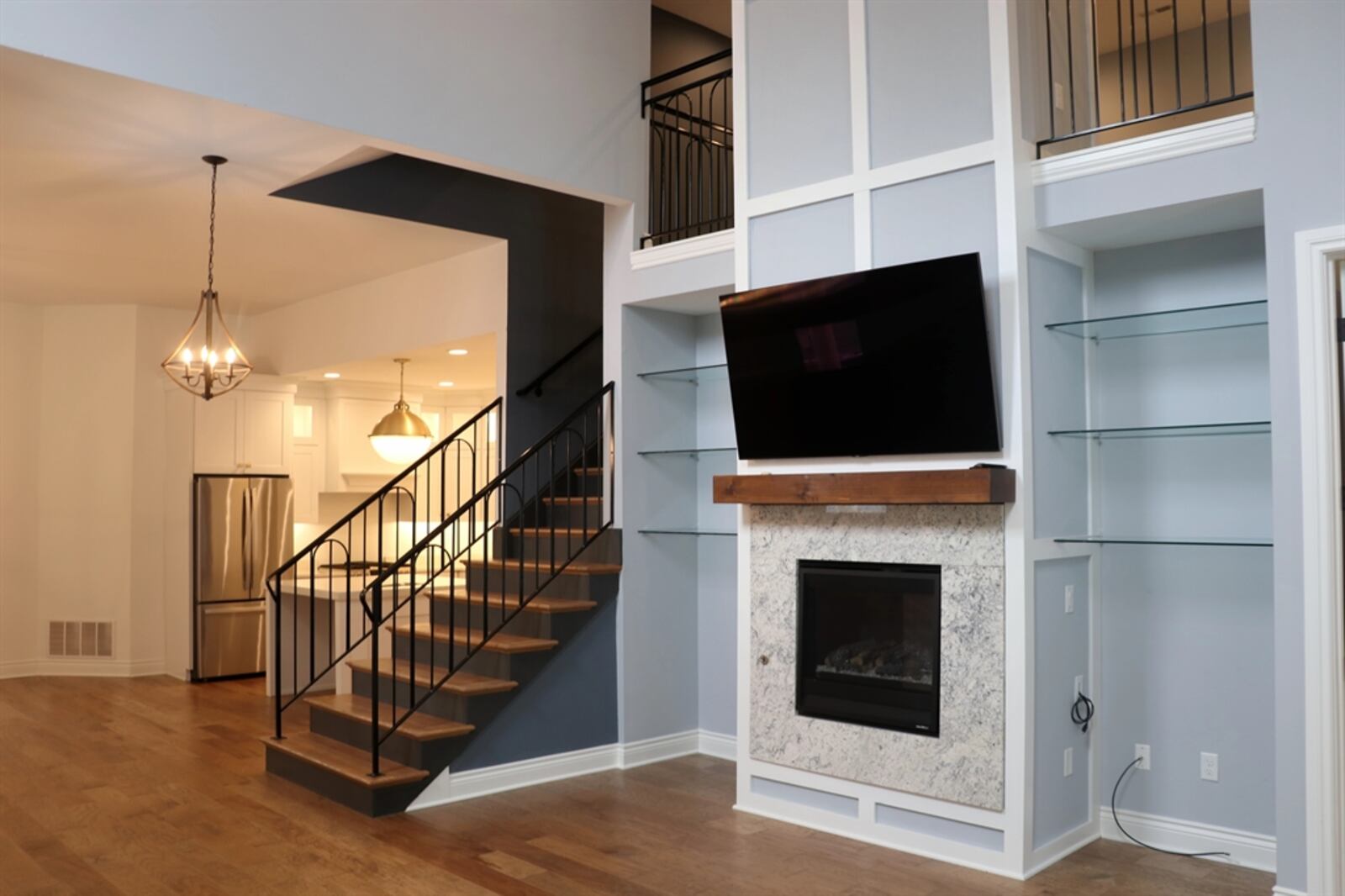 An open wooden staircase with wrought-iron railing divides the dining area from the great room. Windows fill the tall wall, allowing natural light to filter into the upstairs loft. A two-story fireplace has a Heat-and-Glo gas fireplace. CONTRIBUTED BY KATHY TYLER