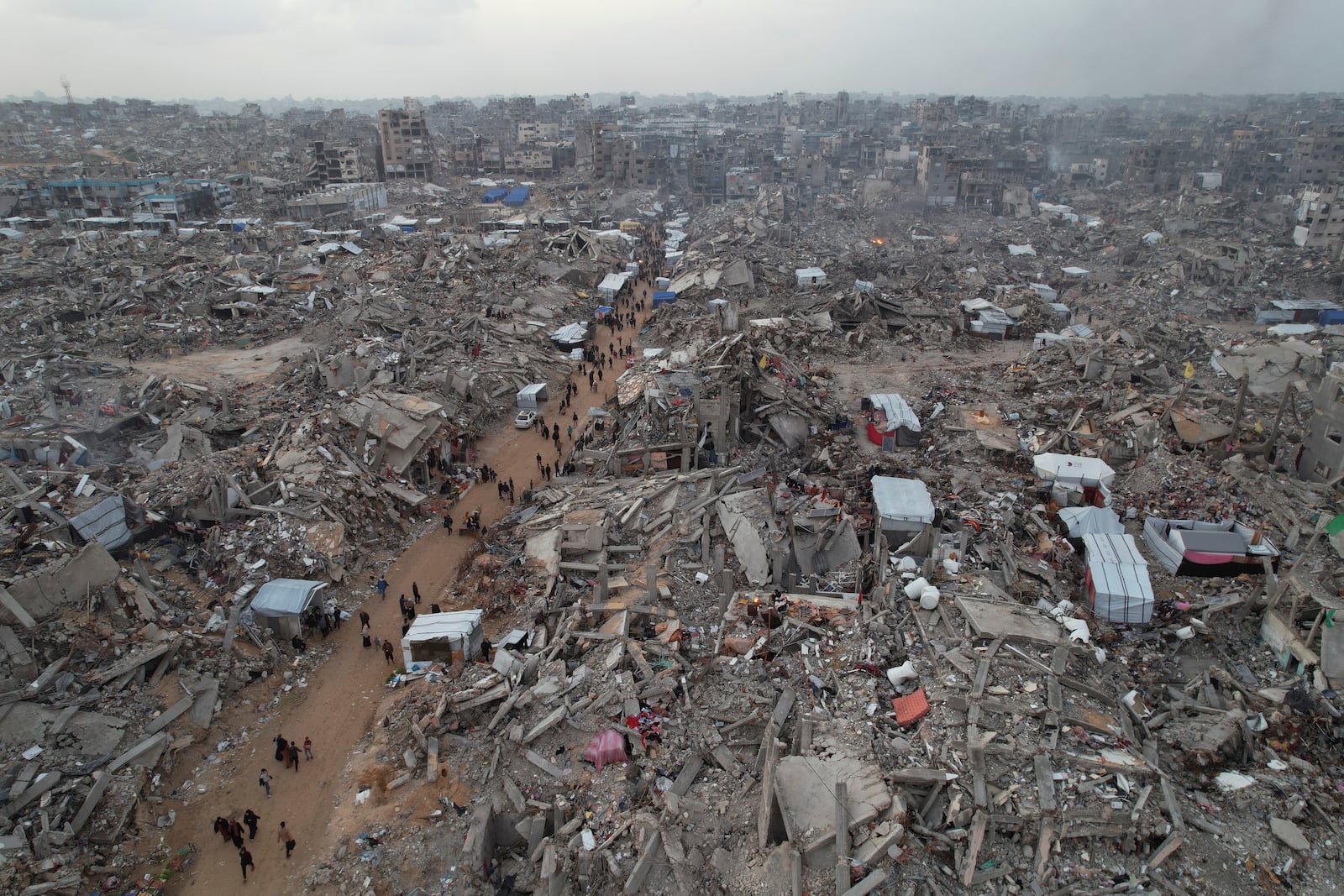 An aerial photograph taken by a drone shows people walking between the destruction caused by the Israeli air and ground offensive in Jabaliya, Gaza Strip, on Sunday, Feb. 16, 2025. (AP Photo/Mohammad Abu Samra)