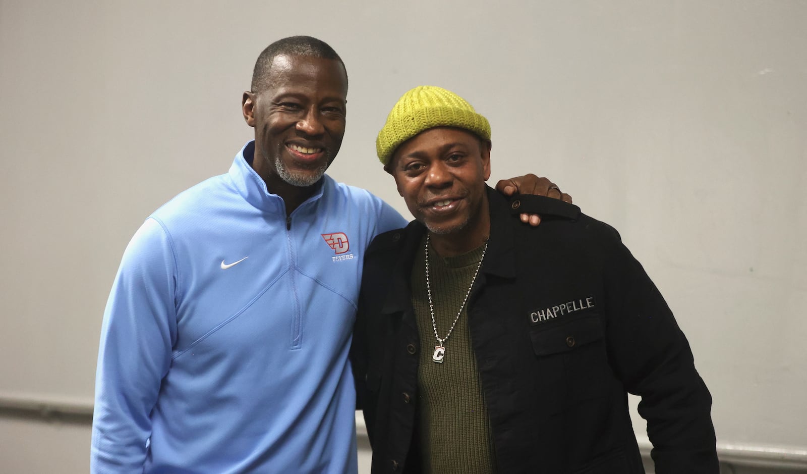 Comedian Dave Chappelle, right, poses for a photo with Dayton coach Anthony Grant after a game against Saint Louis on Tuesday, March 4, 2025, at UD Arena. Chappelle, a longtime Yellow Springs resident, visited UD Arena for the first time. David Jablonski/Staff