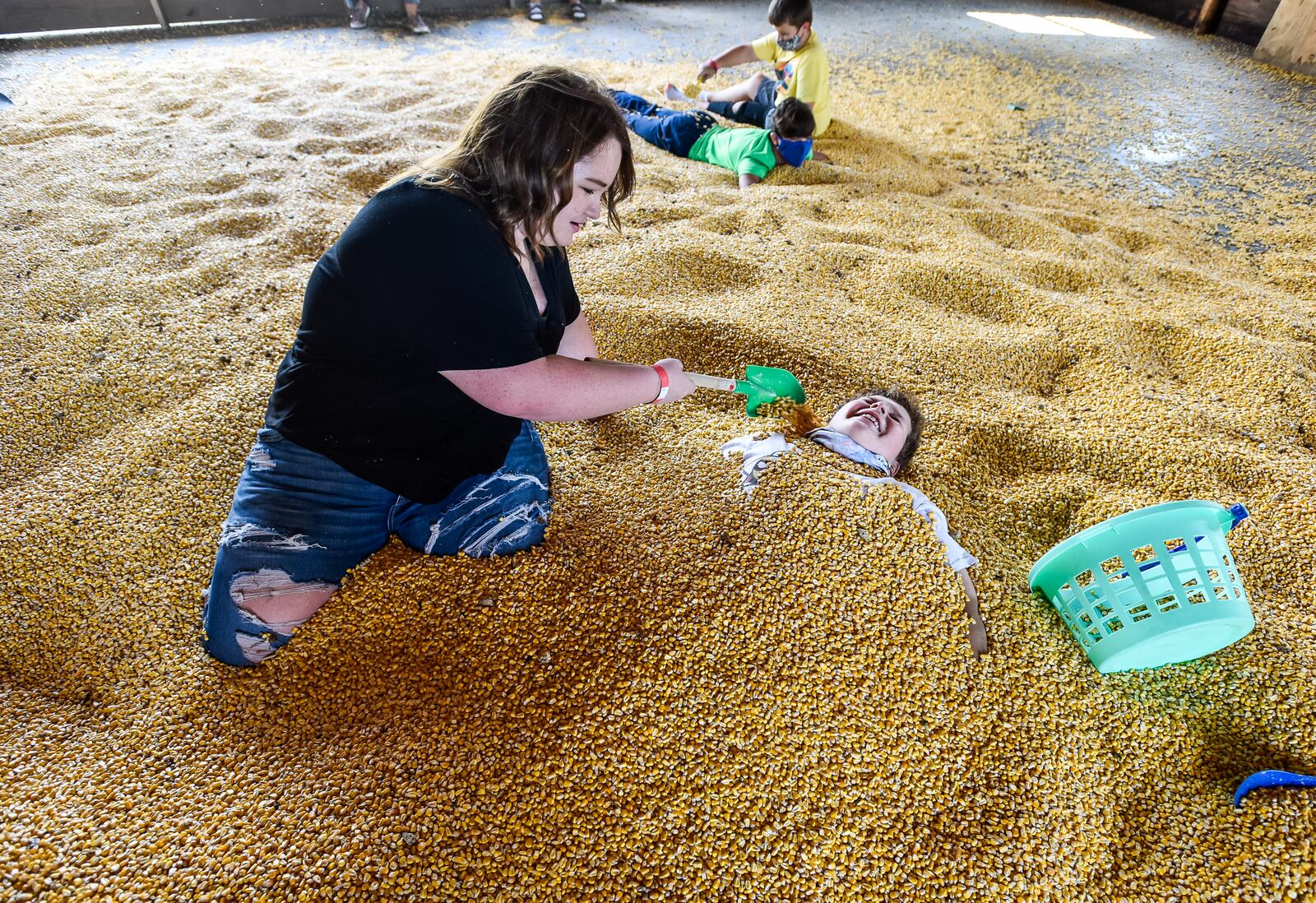 Gracie Barnett, 13, pours orn over Evan Simmons, 11, in the corn barn at Jackson Family Farm Sunday, Sept. 27, 2020 in Madison Township. Fall on the Farm at Jackson Family Farm is open on weekends through October 25 on West Alexandria Road in Madison Township. The educational farm experience features pedal tractors, pumpkin patch, farm animals, corn maze, hay tower, hayride to the cattle field, pumpkin jump pad and more. NICK GRAHAM / STAFF