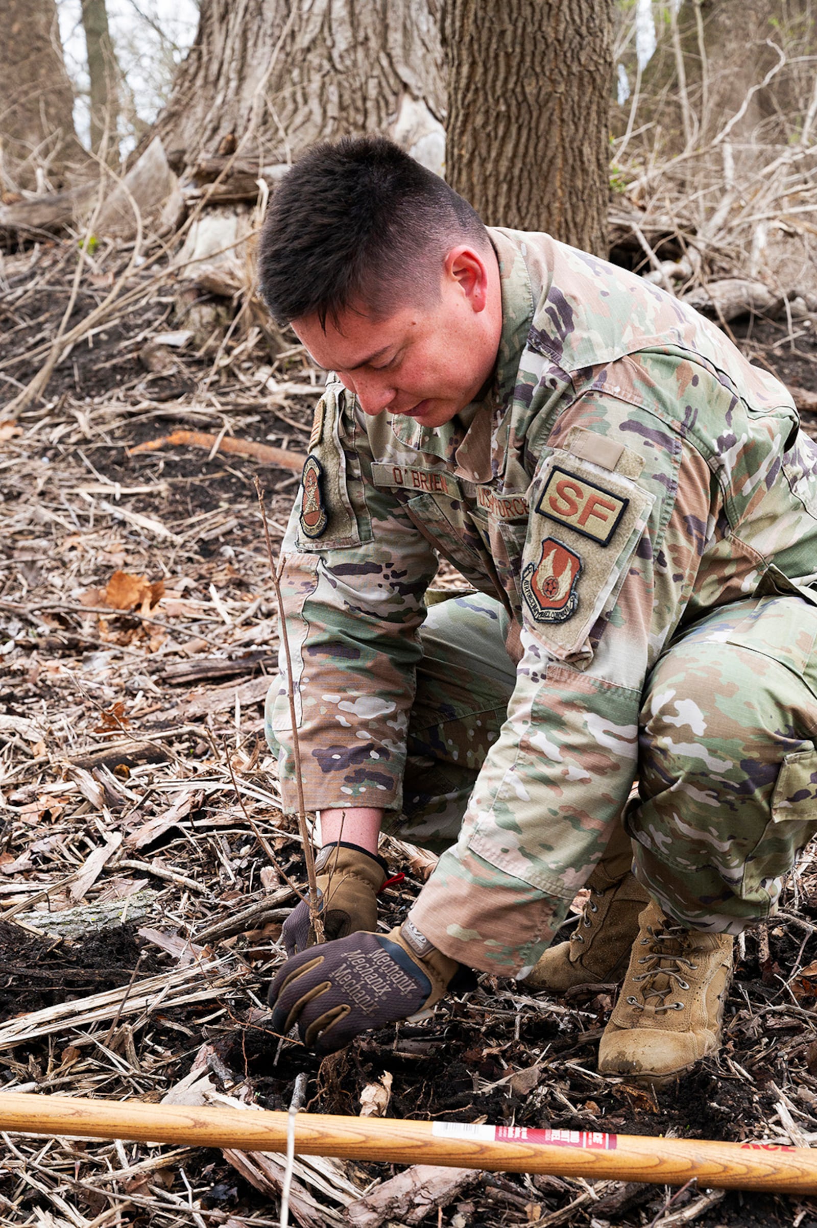 First Lt. Justin O’Brien, 88th Security Forces Squadron, plants a seedling April 7 in a wooded area along Trout Creek at Wright-Patterson Air Force Base. The area had recently been cleared of invasive honeysuckle, and 180 seedlings of various native trees were planted to provide homes to wildlife, including an endangered bat species. U.S. AIR FORCE PHOTO/R.J. ORIEZ