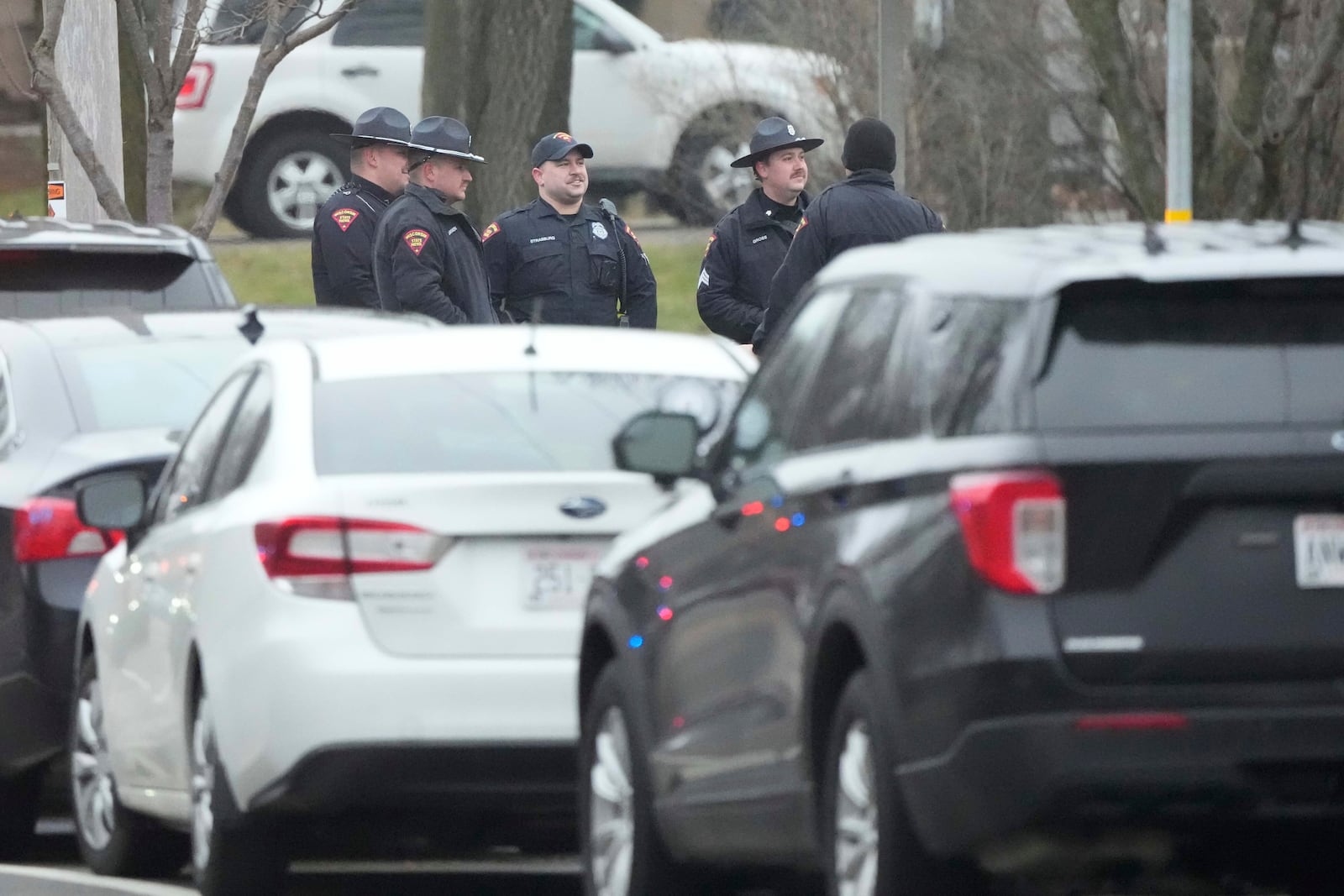 Police gather as emergency vehicles are parked outside the Abundant Life Christian School in Madison, Wis., where multiple injuries were reported following a shooting, Monday, Dec. 16, 2024. (AP Photo/Morry Gash)