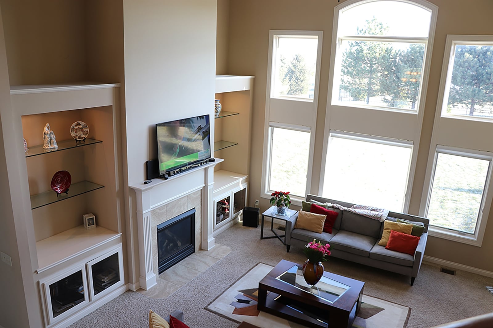 The great room has an 18-foot ceiling that allows for a wall of windows to fill the room with natural light and offers views of the park and back yard. Another wall has built-in display cases with glass shelves and glass-door cabinets. The display cases flank the gas fireplace, which has a fluted wood mantel with media connections. CONTRIBUTED PHOTO BY KATHY TYLER